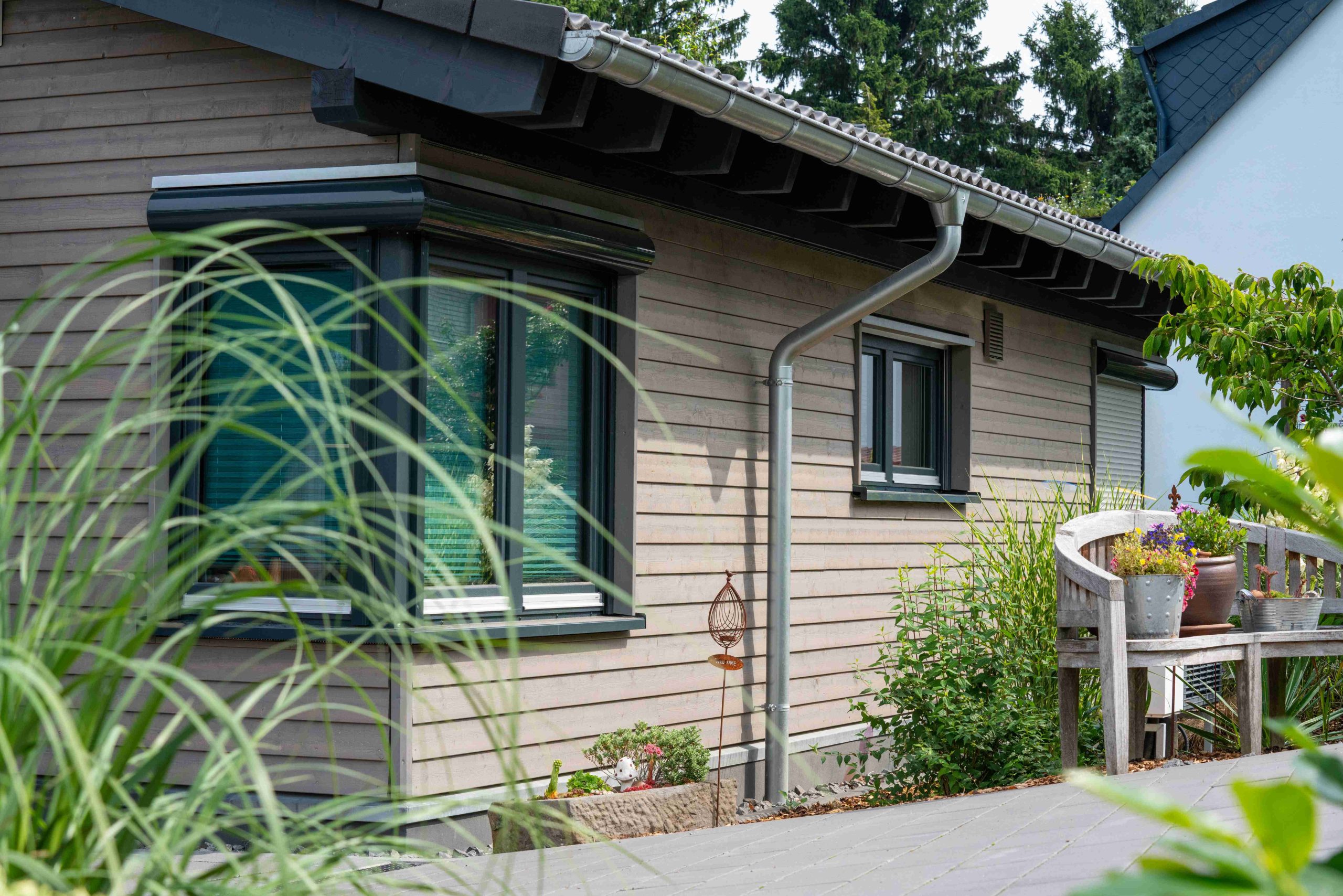 Holz-Bungalow mit grauer Fassade und bepflanztem Vorgarten