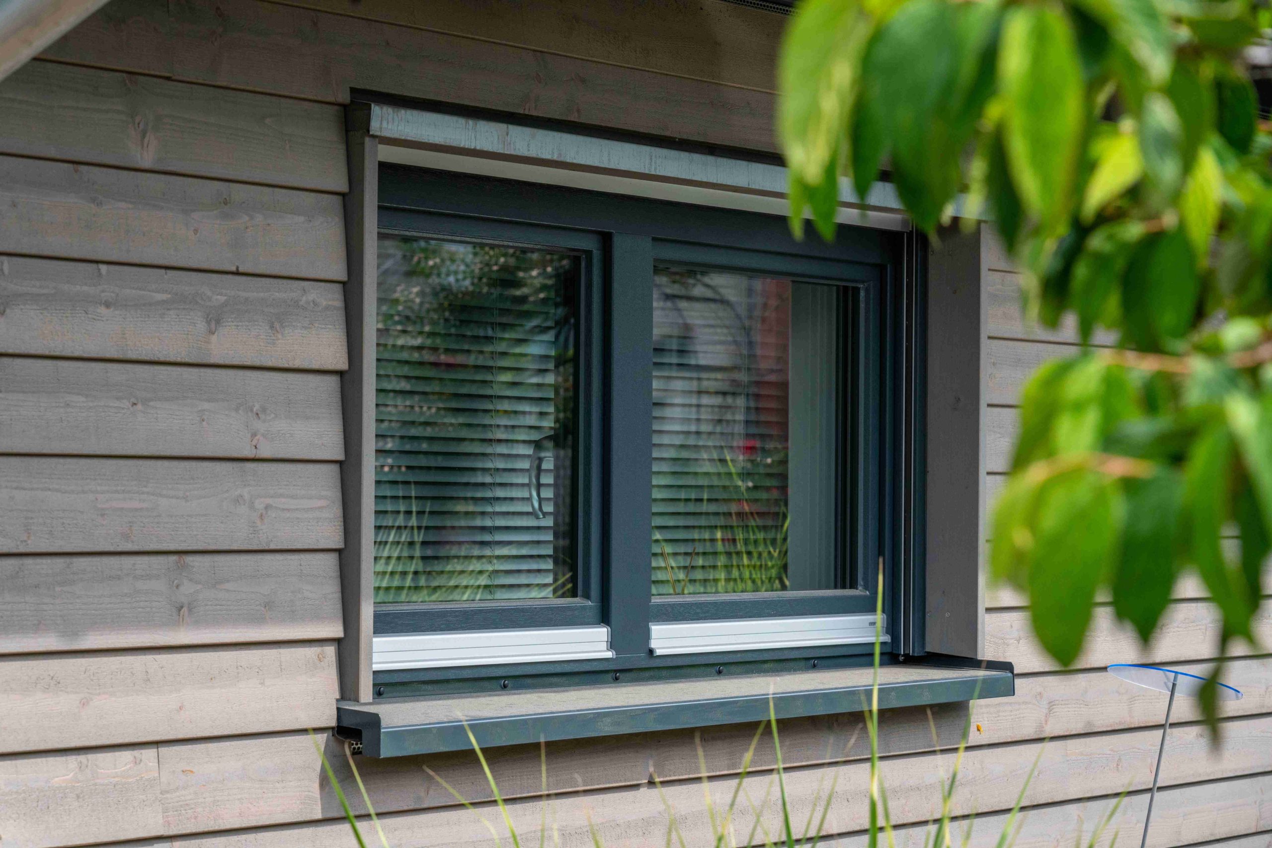 Nahaufnahme eines grauen Holzfensters mit Beschattung