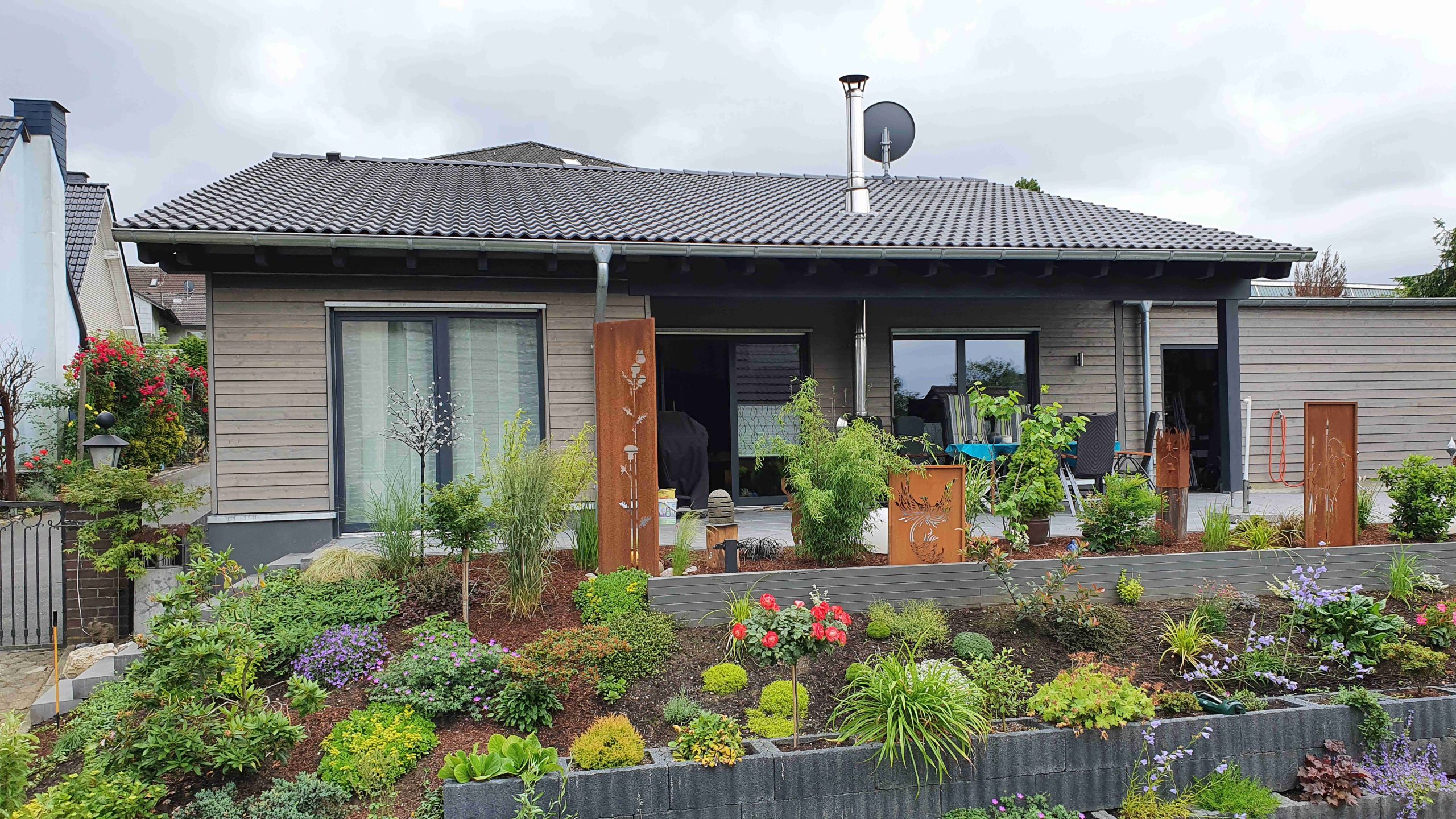 Rückansicht des Holz-Bungalows mit bepflanztem Garten