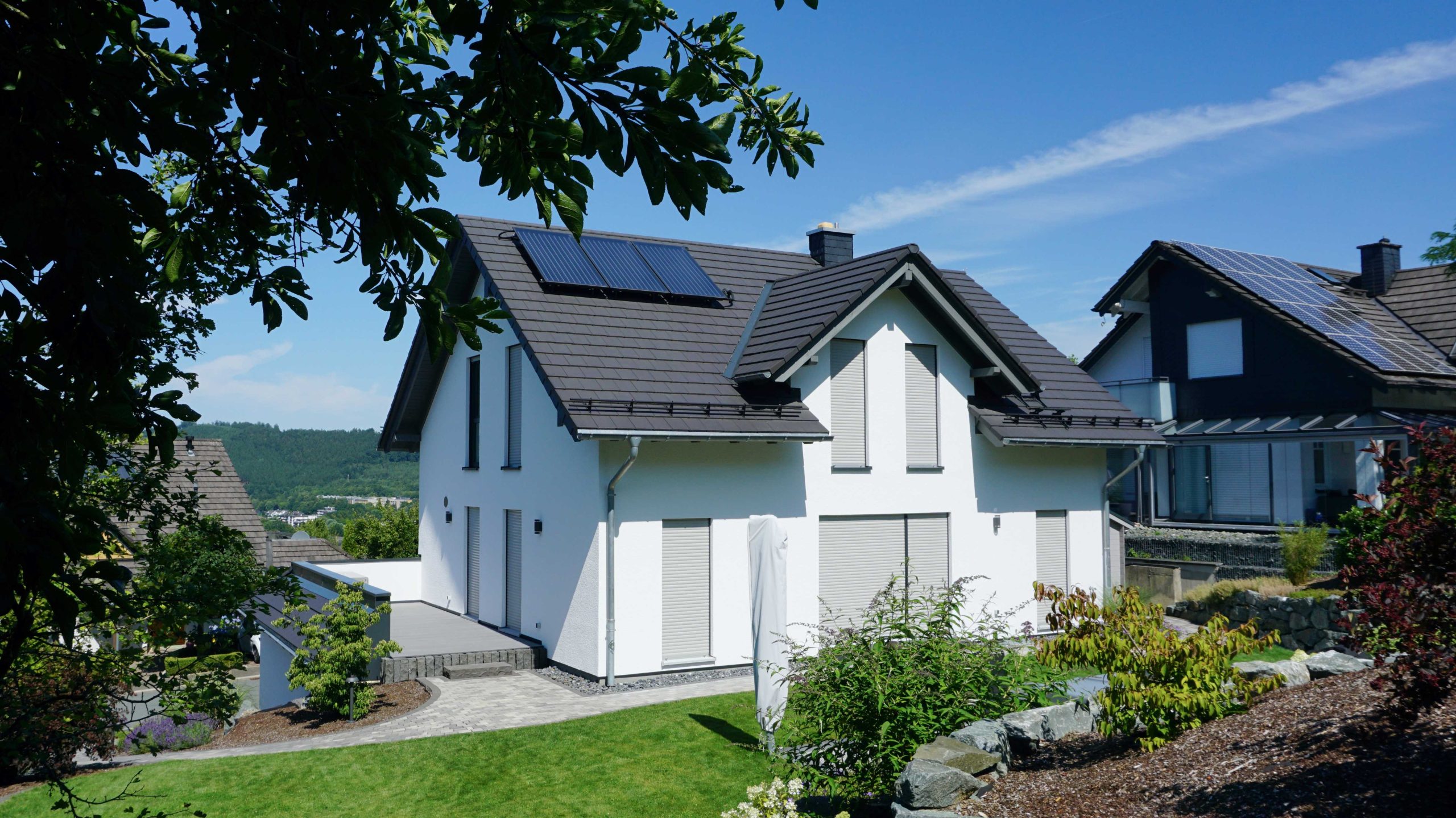 Rückansicht des Einfamilienhauses mit Satteldach, Solaranlage und weitem Blick über die Hanglage