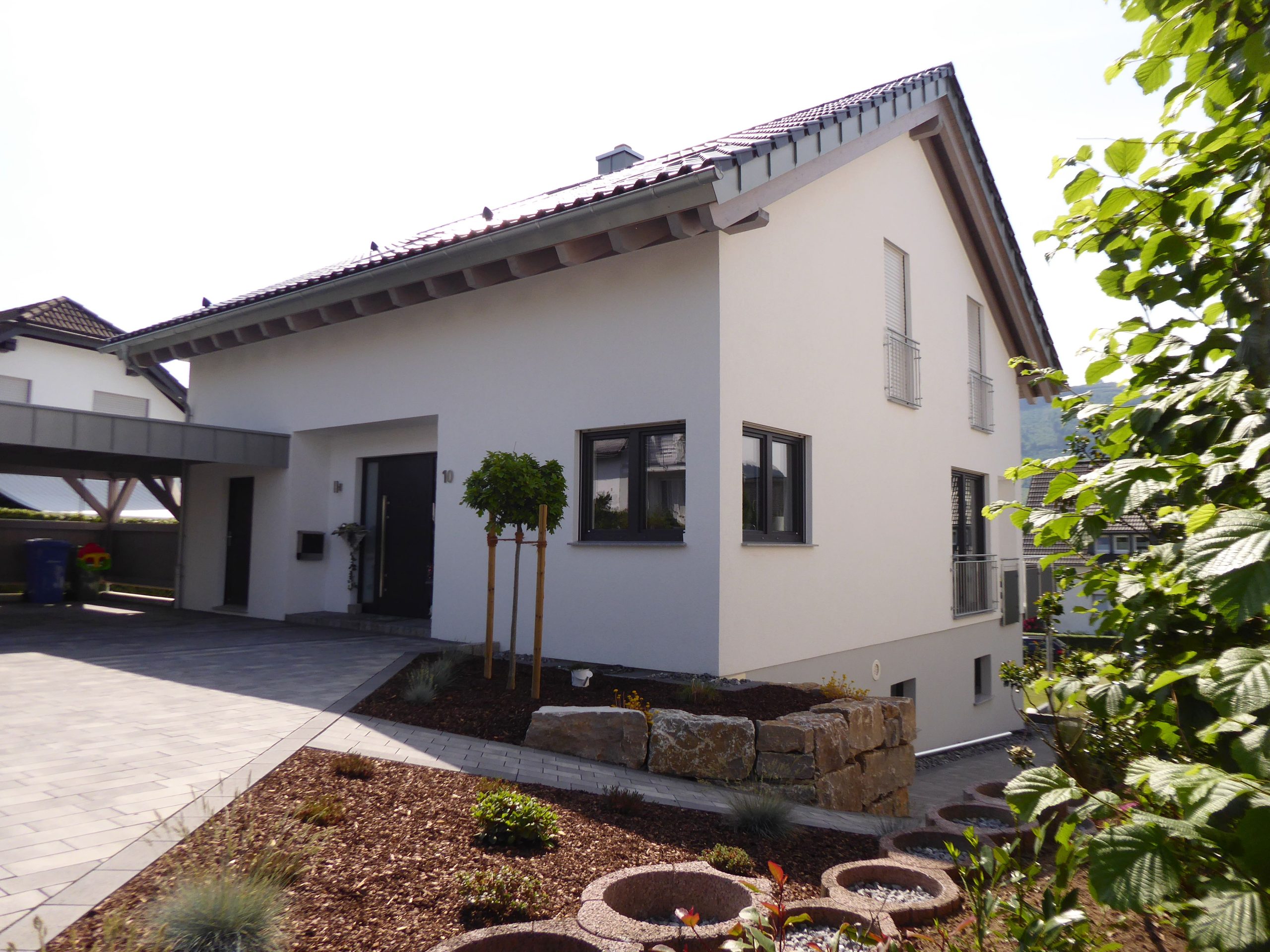 Frontalansicht des Hauseingangs von Haus Vollmer mit dunkler Haustür, seitlichem Glasfeld und gepflastertem Vorbereich