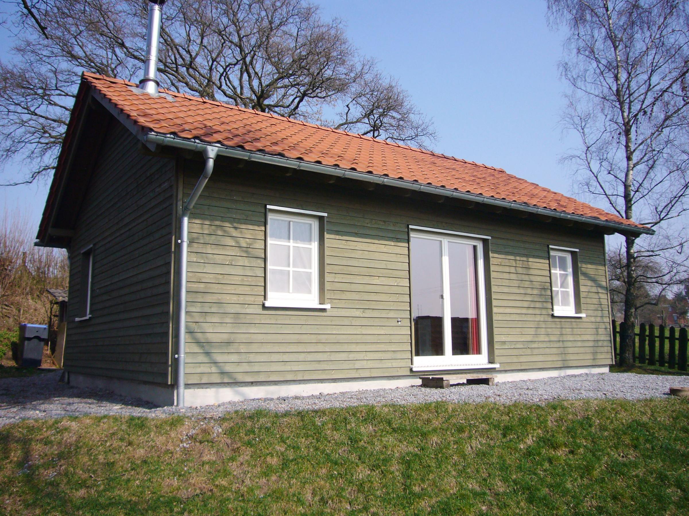 Außenansicht eines kompakten Holzferienhauses mit grüner Fassadenverschalung und Terrassentür