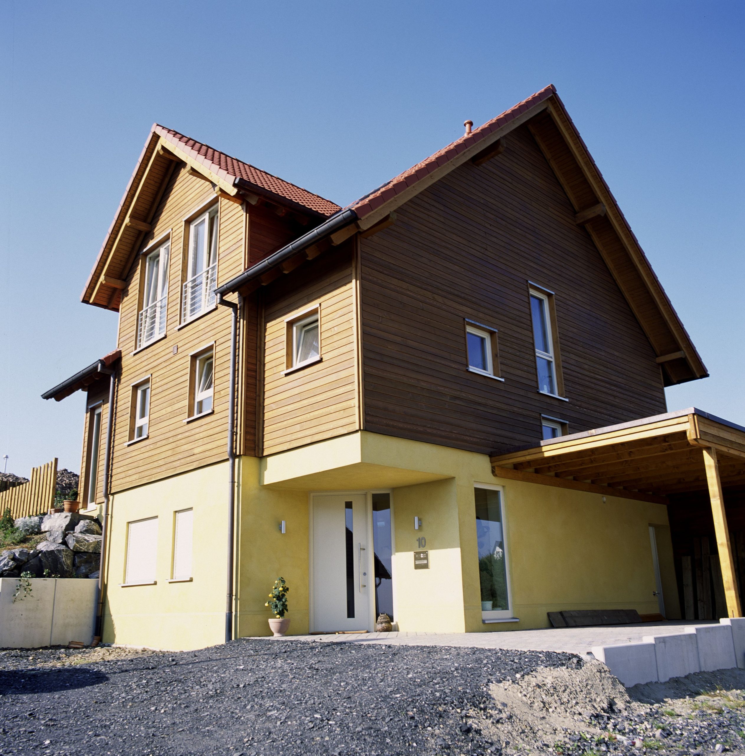 Außenseite des Haus Asprion mit gelbem Sockelbereich und Holzfassade