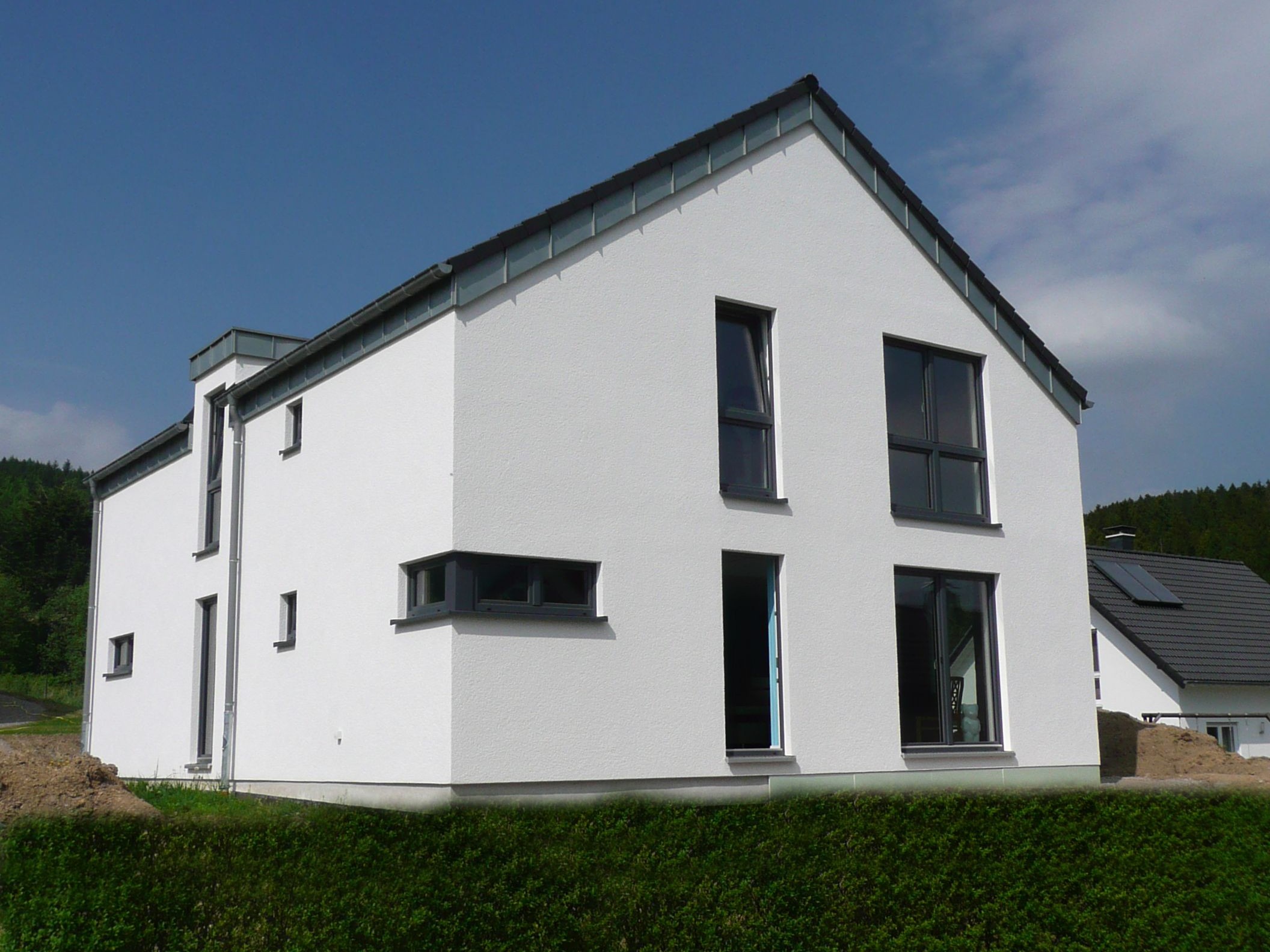 Giebelseitige Außenansicht eines Einfamilienhauses mit weißer Putzfassade