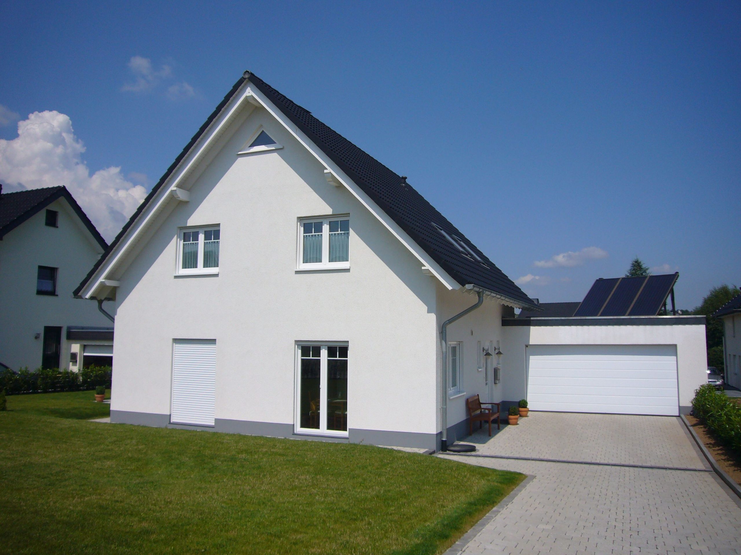 Einfamilienhaus mit angebauter Garage, weißer Putzfassade und dunklem Satteldach