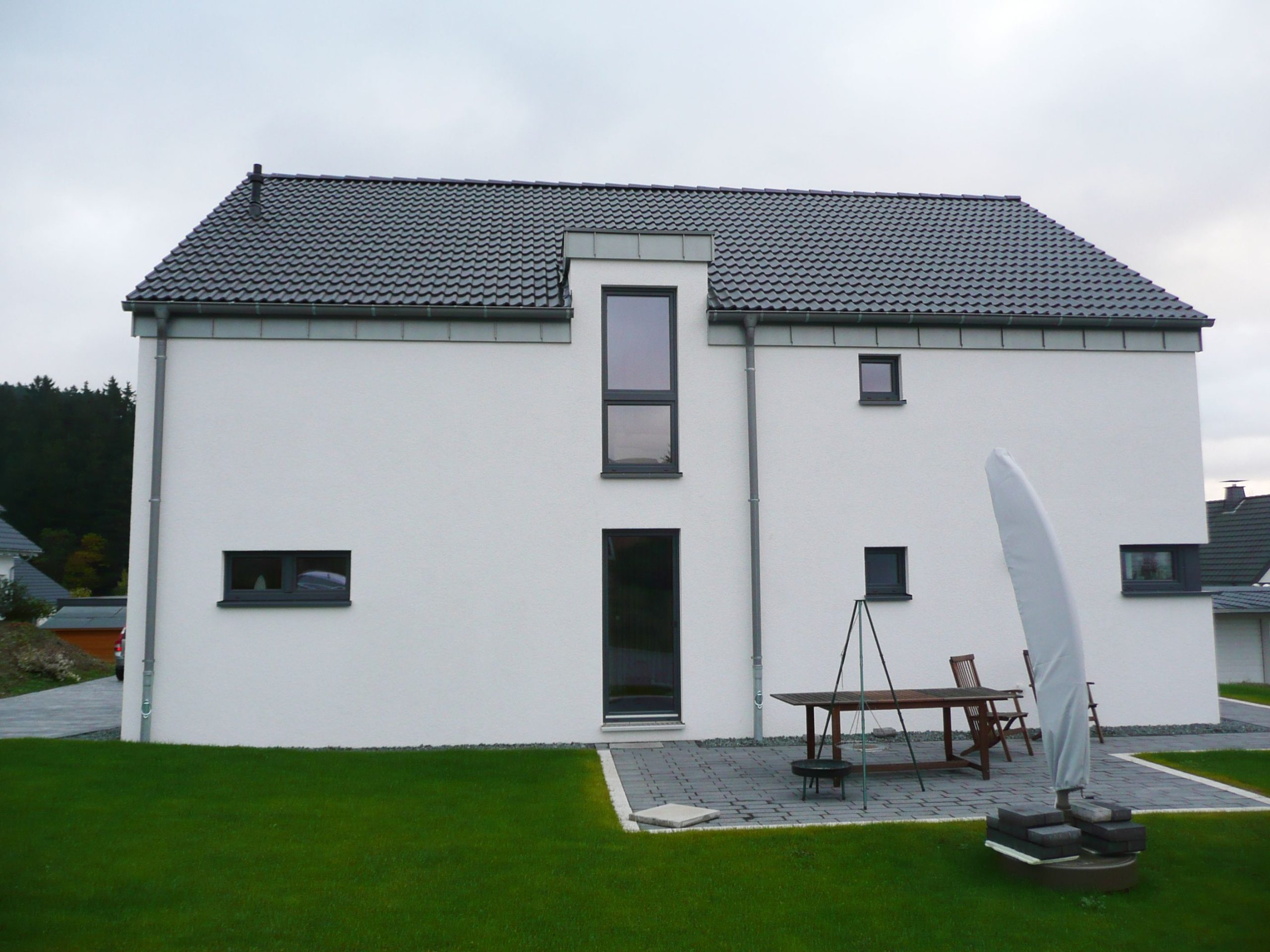 Außenansicht eines Holzhauses mit reduziertem Dachüberstand und Terrasse