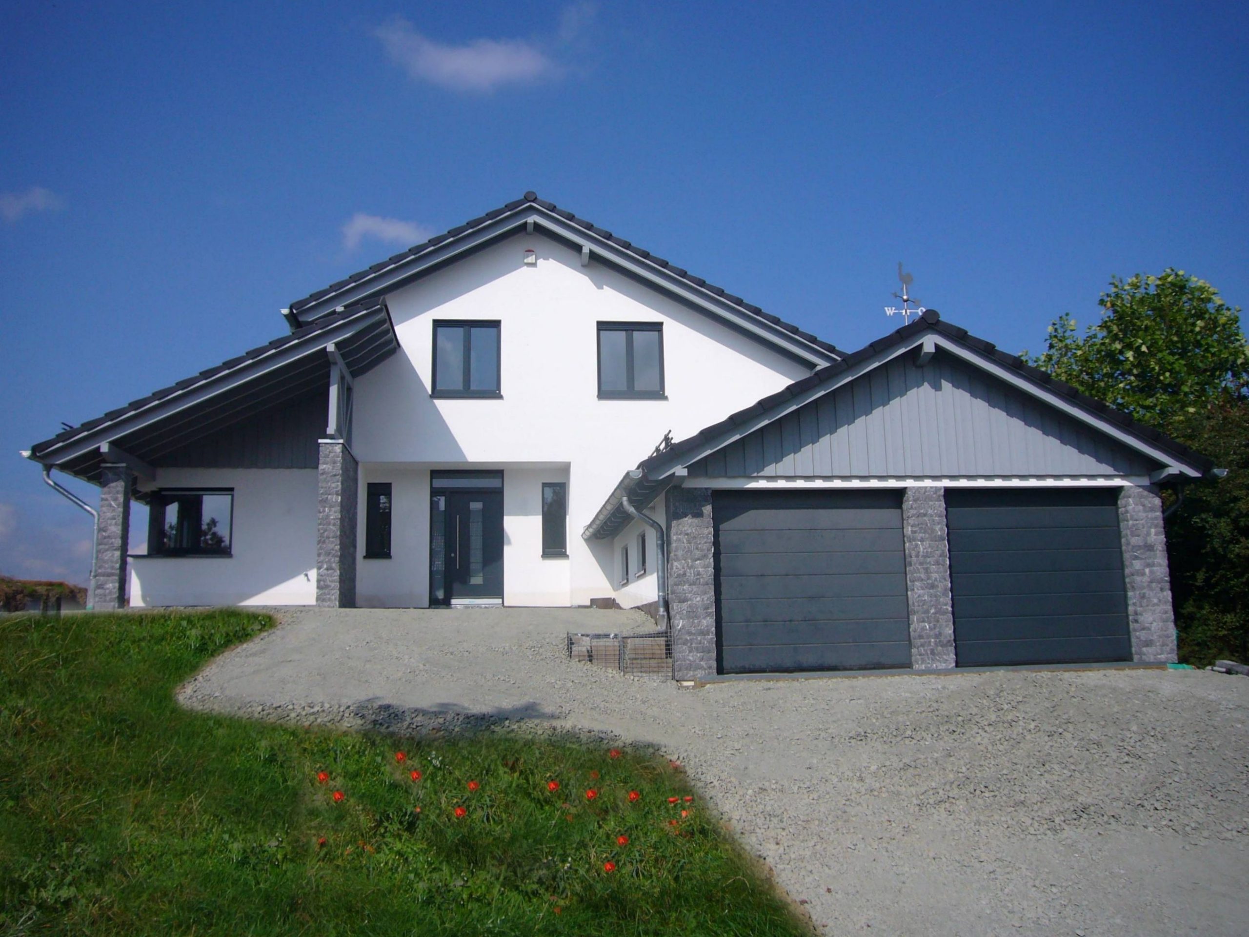 Frontansicht eines Einfamilienhauses mit Doppelgarage und Natursteinstützen