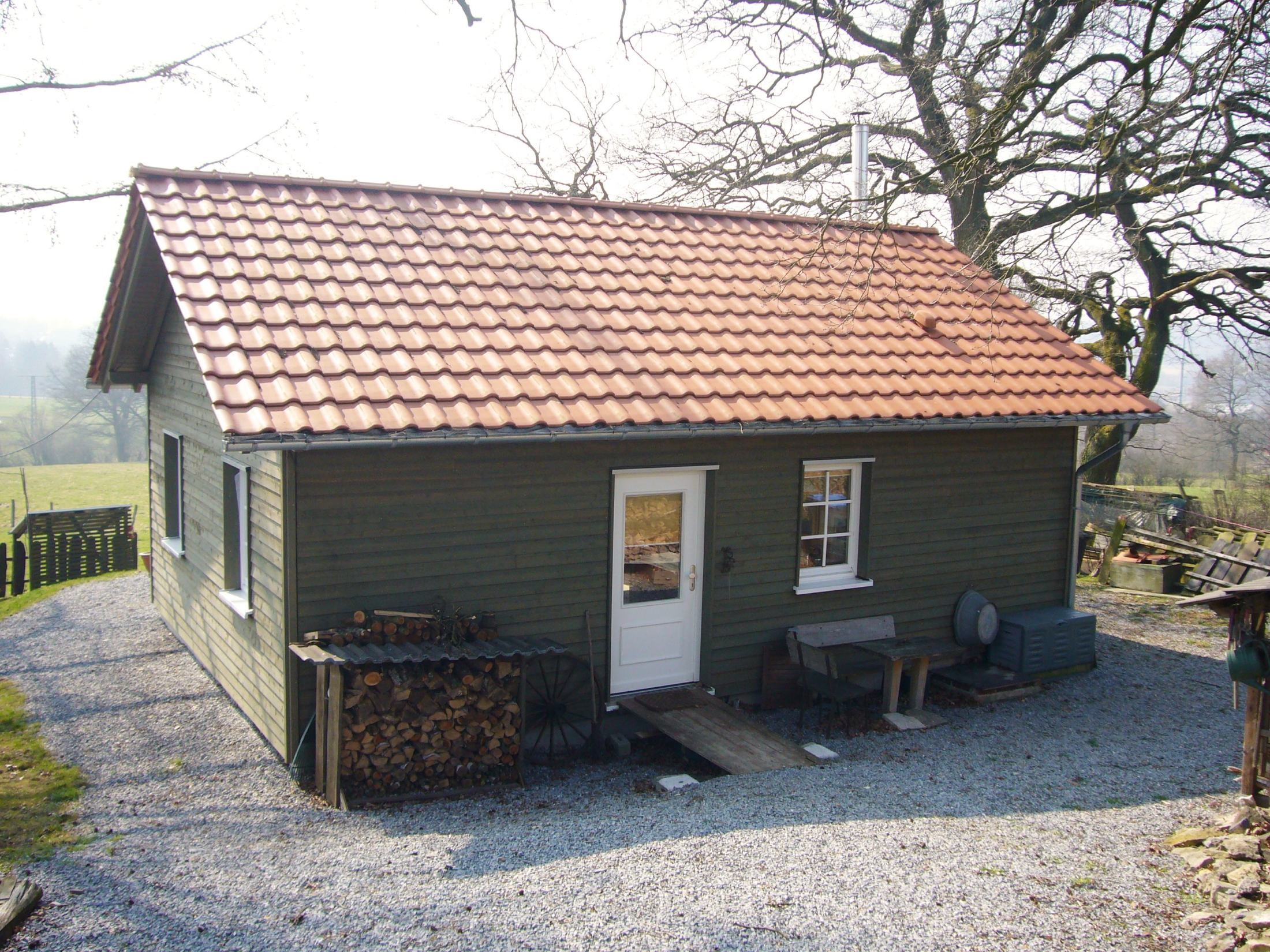 Realisiertes Ferienhaus aus Holz mit Satteldach, Holzschalung und naturnaher Umgebung