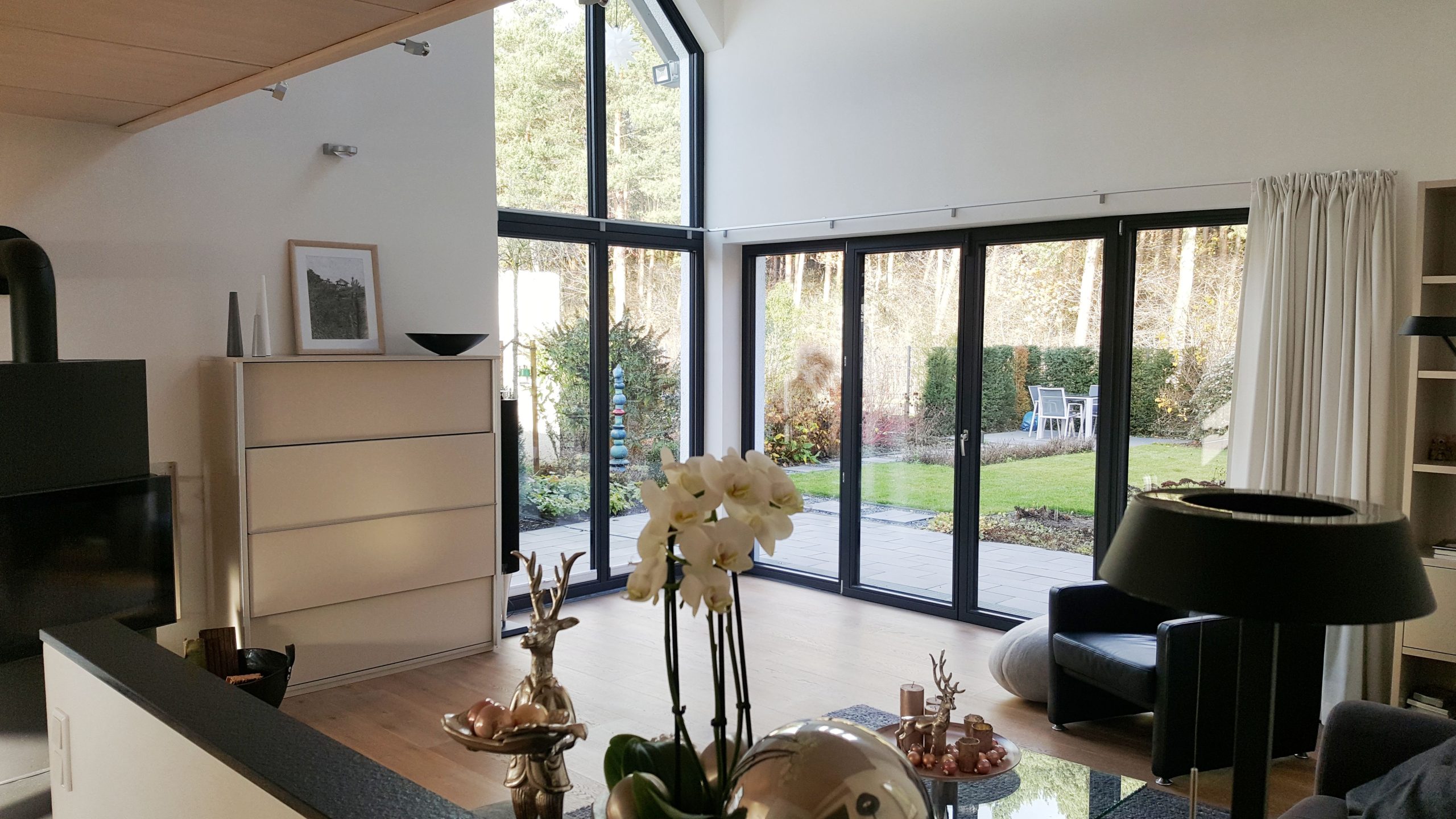 Großzügiger Wohnraum mit bodentiefen Fenstern, Blick ins Grüne und moderner Einrichtung