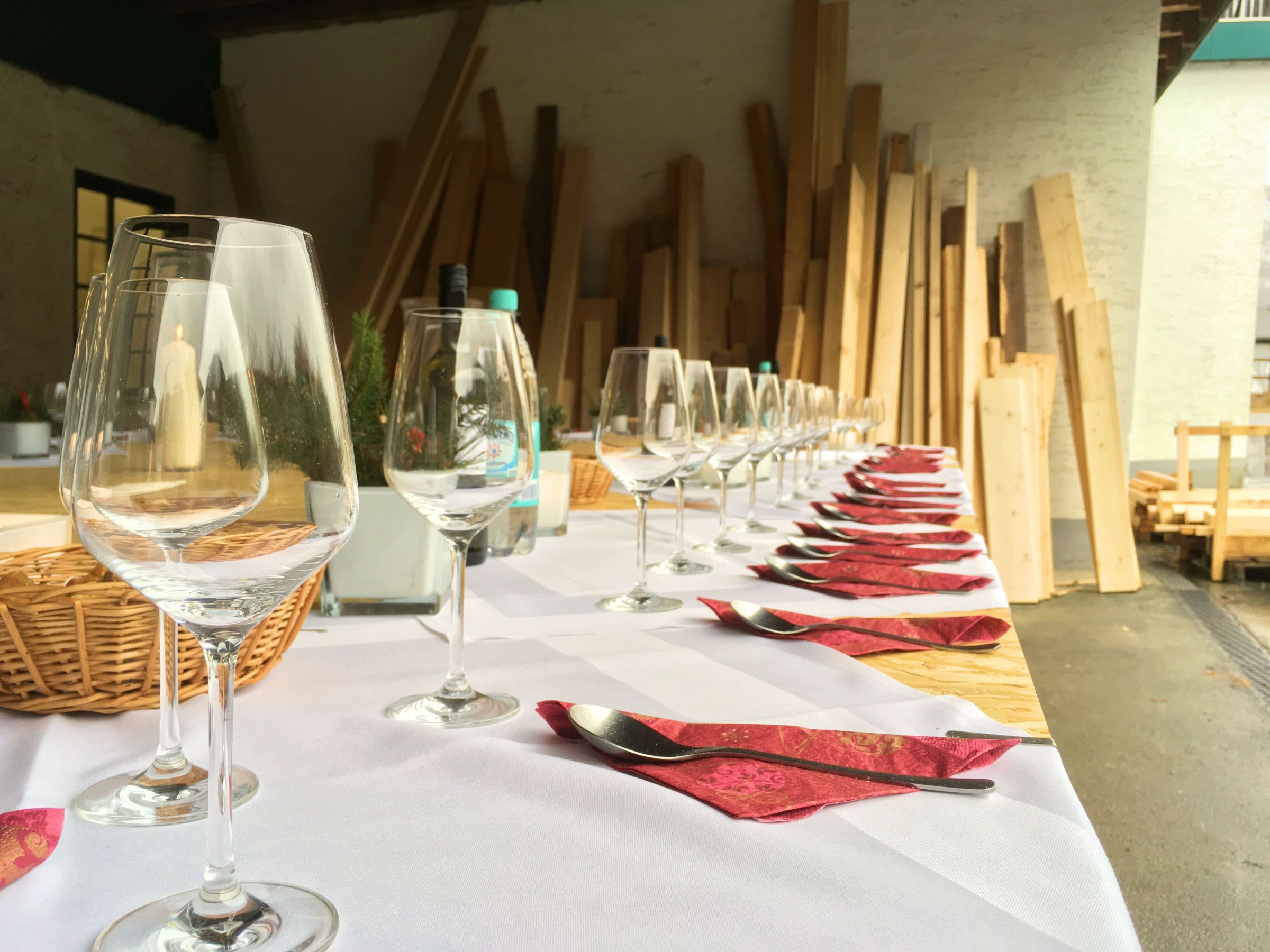 Detailansicht einer gedeckten Tafel mit Gläsern und Besteck in einer Holzwerkstatt