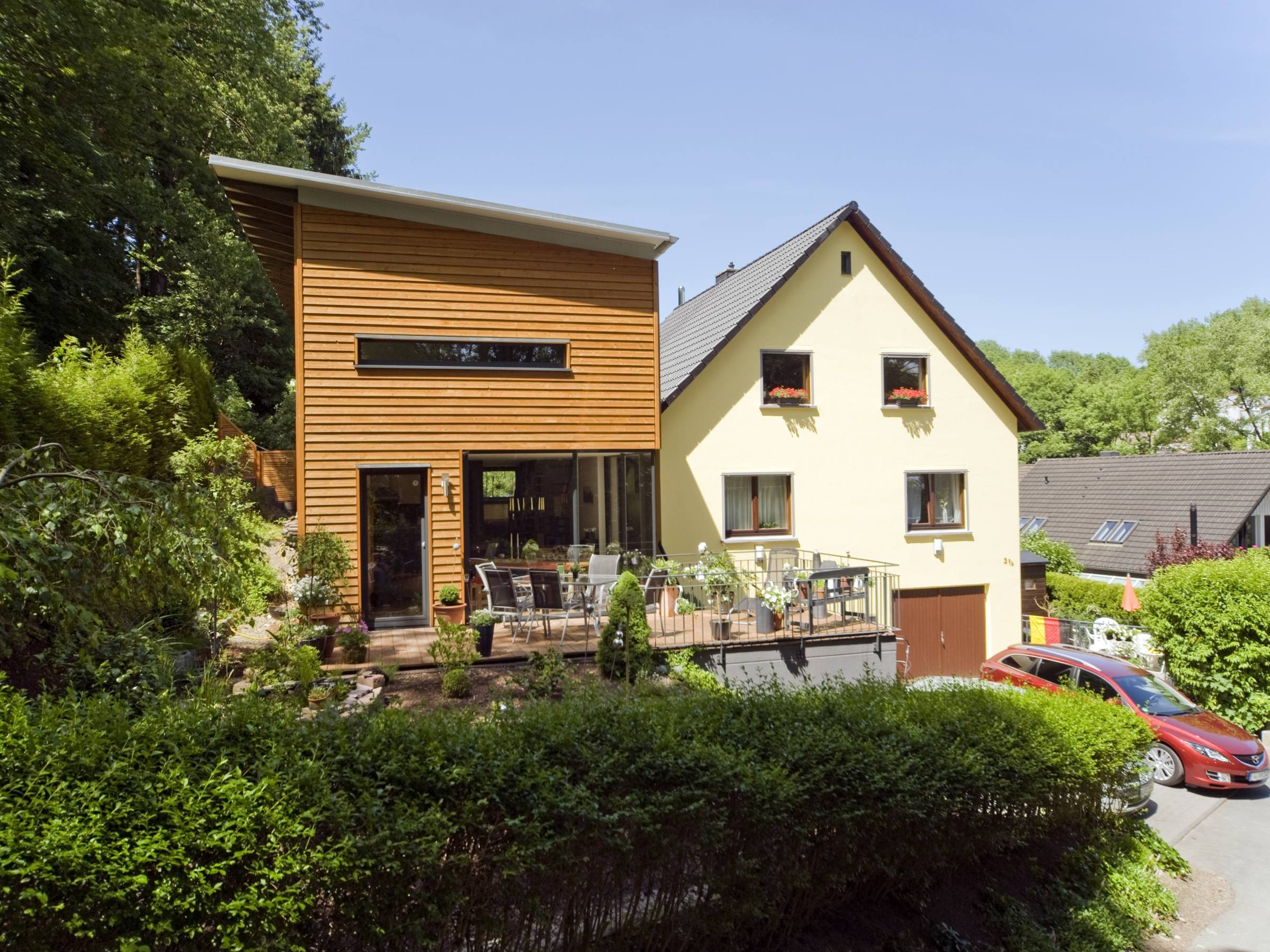 Zweigeschossiger Holzanbau mit Terrasse als Erweiterung eines bestehenden Wohnhauses