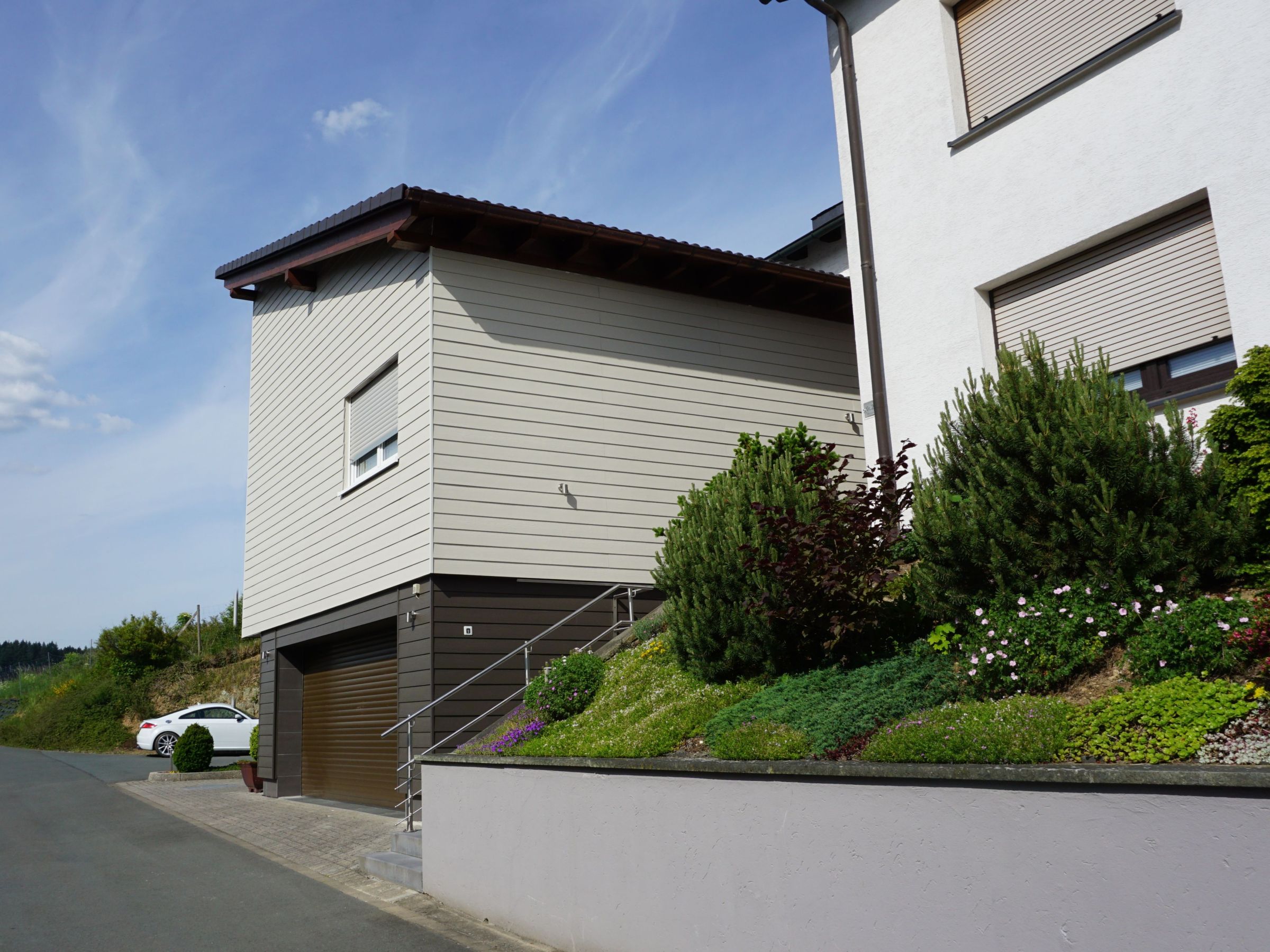 Dunkel abgesetzter Garagensockel unter dem zweigeschossigen Anbau