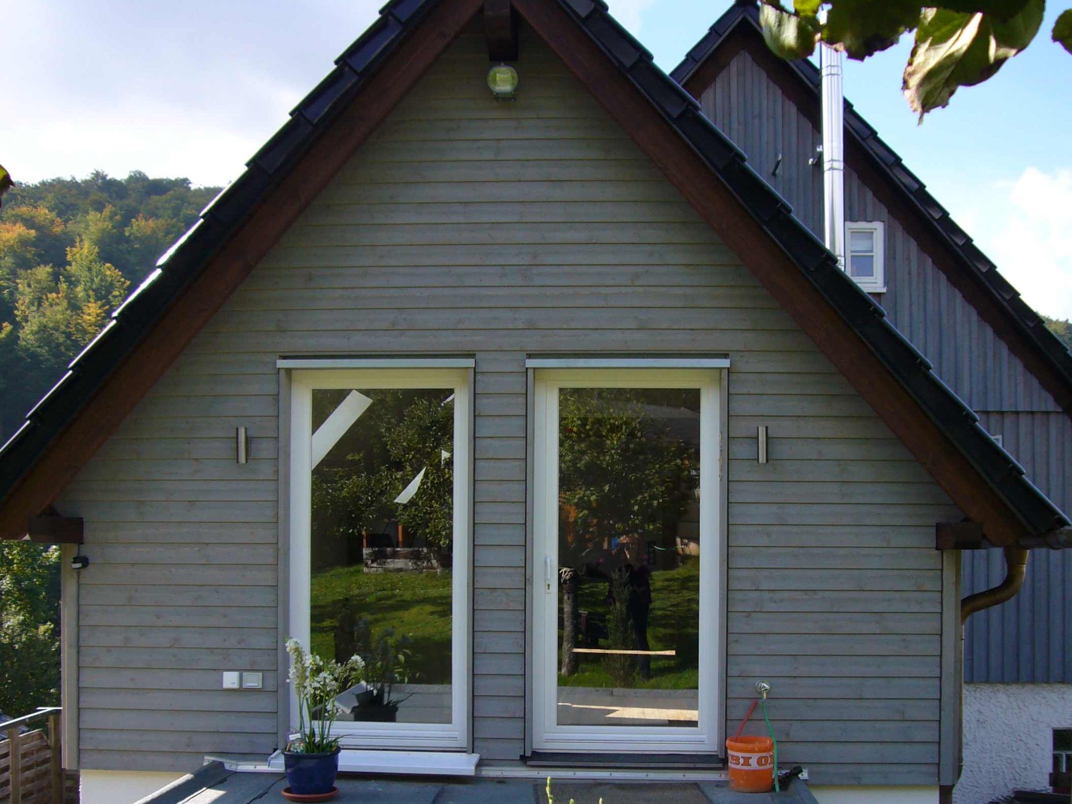 Detail der horizontalen Holzfassade des zweigeschossigen Anbaus mit bodentiefen Fenstern