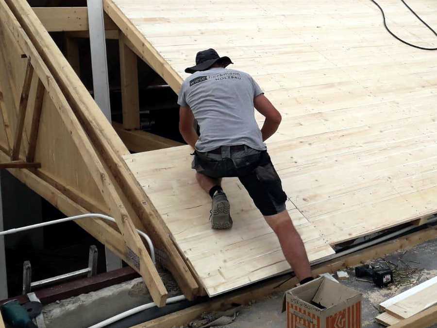 Auszubildender montiert Holzdeckenplatten auf einer Baustelle im Rahmen eines Auslandspraktikums in Namibia