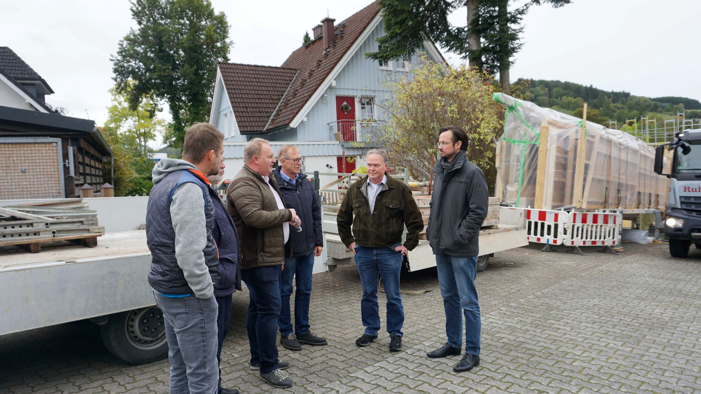 Gespräch mehrerer Personen auf einer Baustelle mit Holzbauelementen in Olsberg