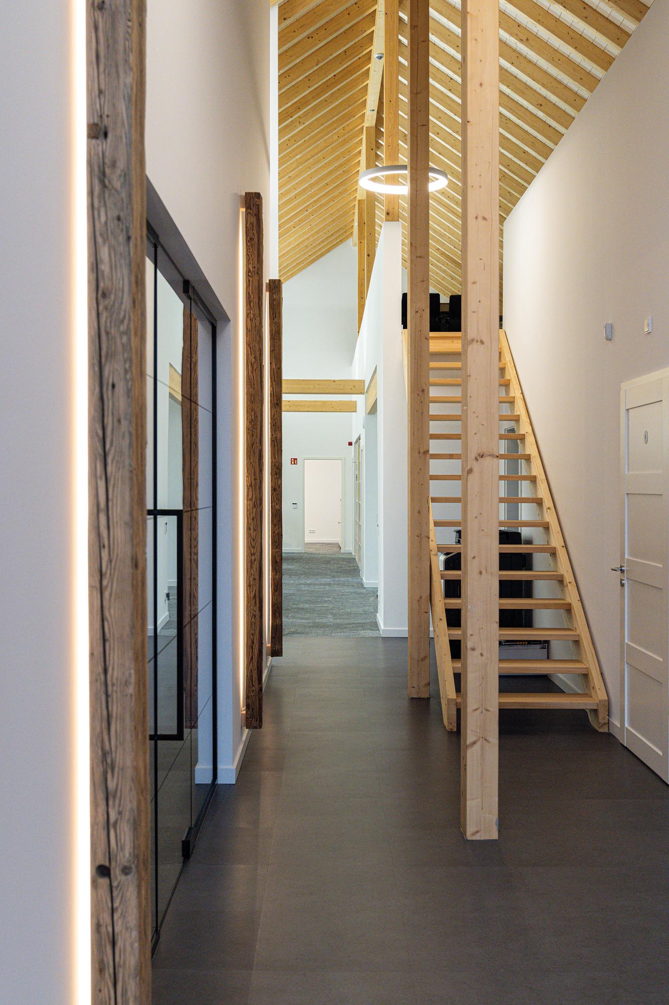 Flurbereich mit Empore, Holzstützen und sichtbarer Dachkonstruktion in einem modernen Bürogebäude