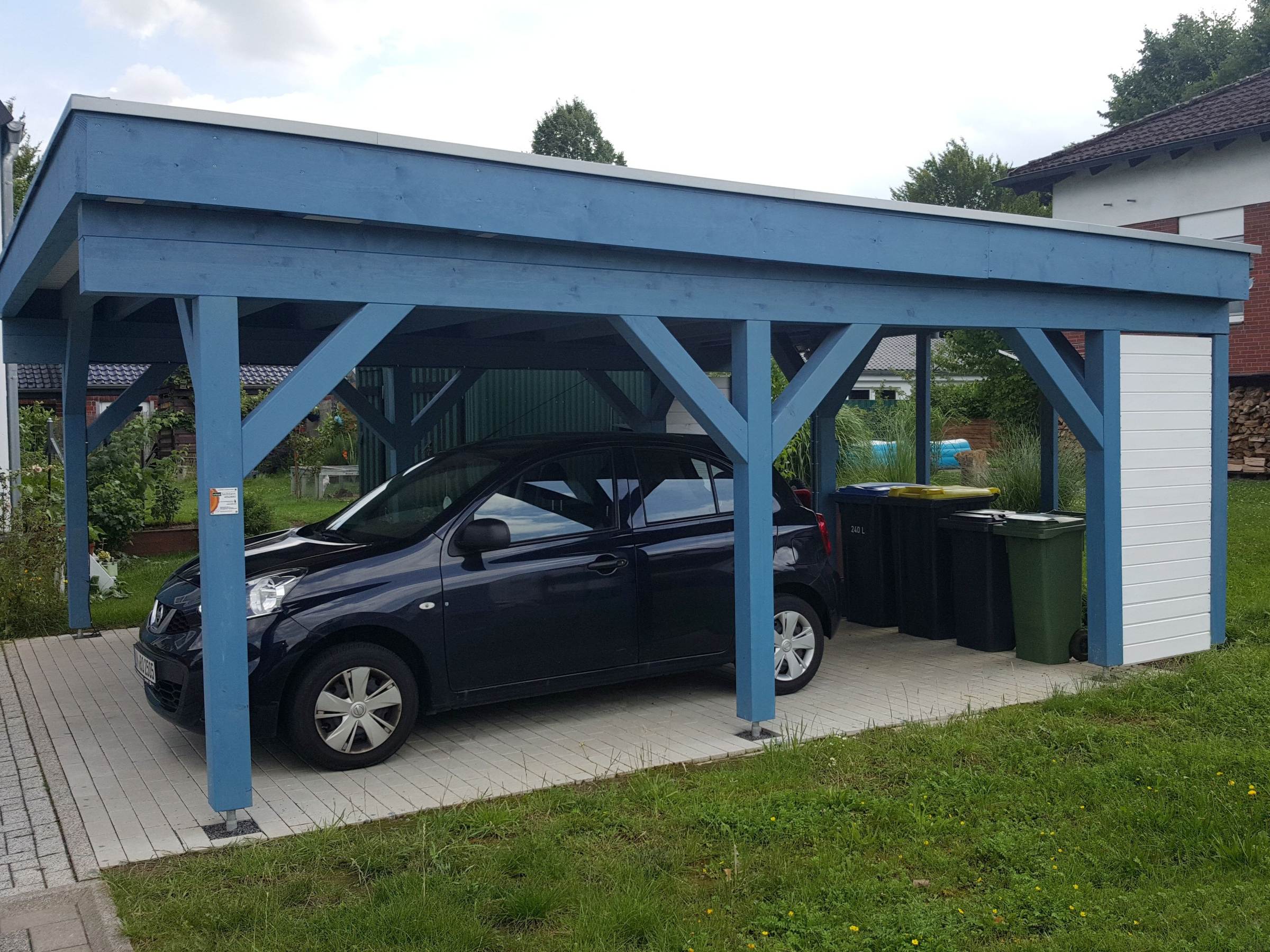 Carport in Holzbauweise neben einem friesenblauen Einfamilienhaus