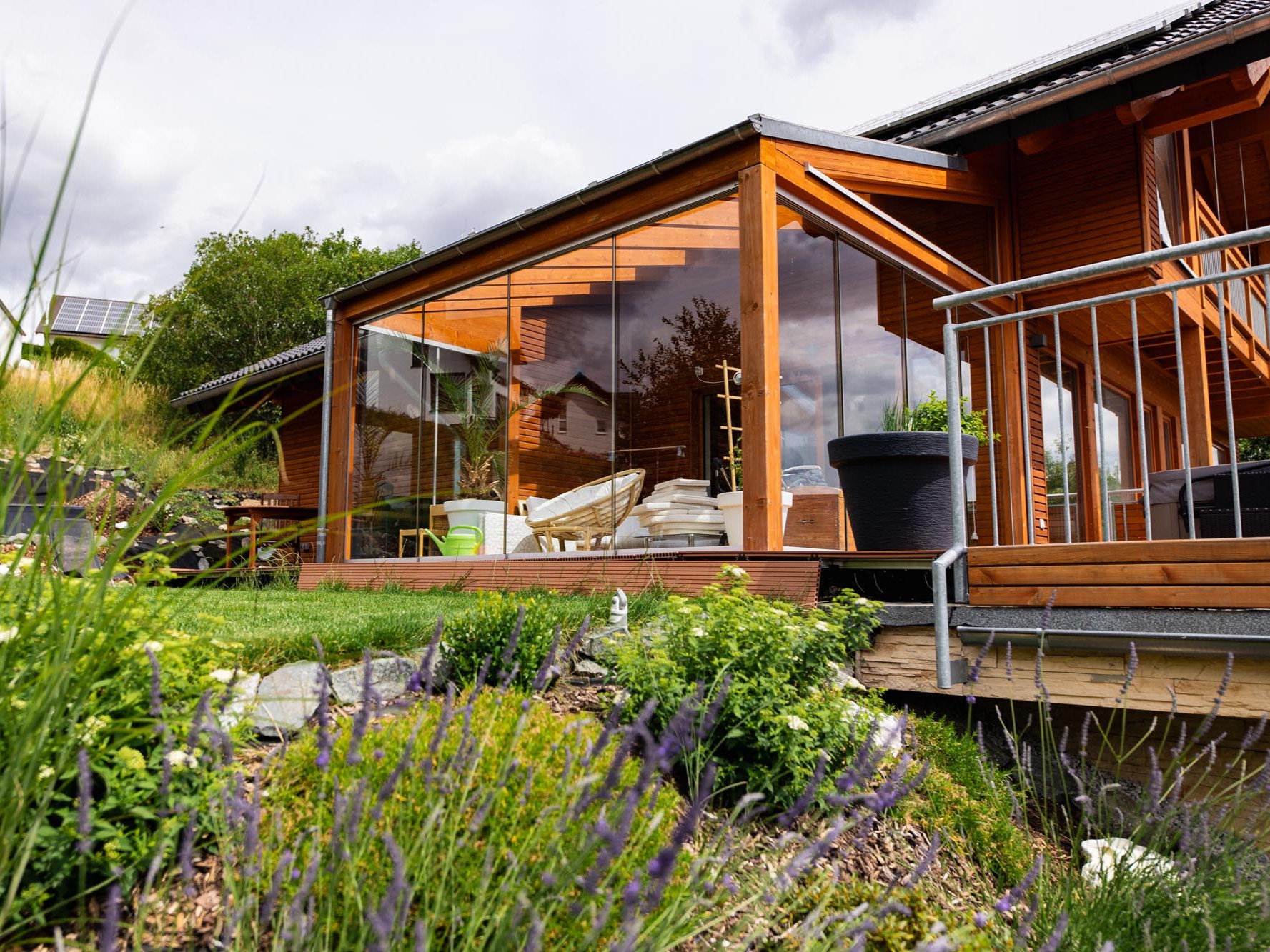 Verglaster Wintergarten mit angrenzender Terrasse und Holzfassade im Gartenbereich