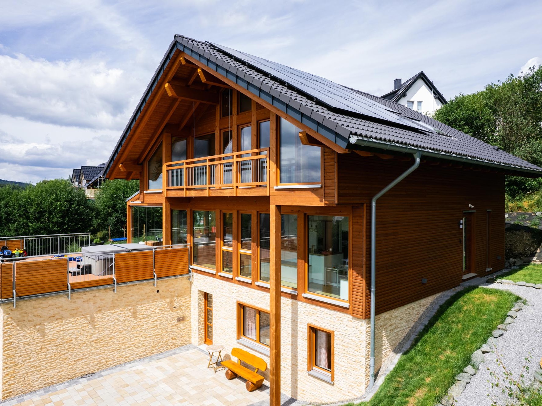 Einfamilienhaus mit Wintergarten, Balkon und waagerechter Holzfassade in Hanglage