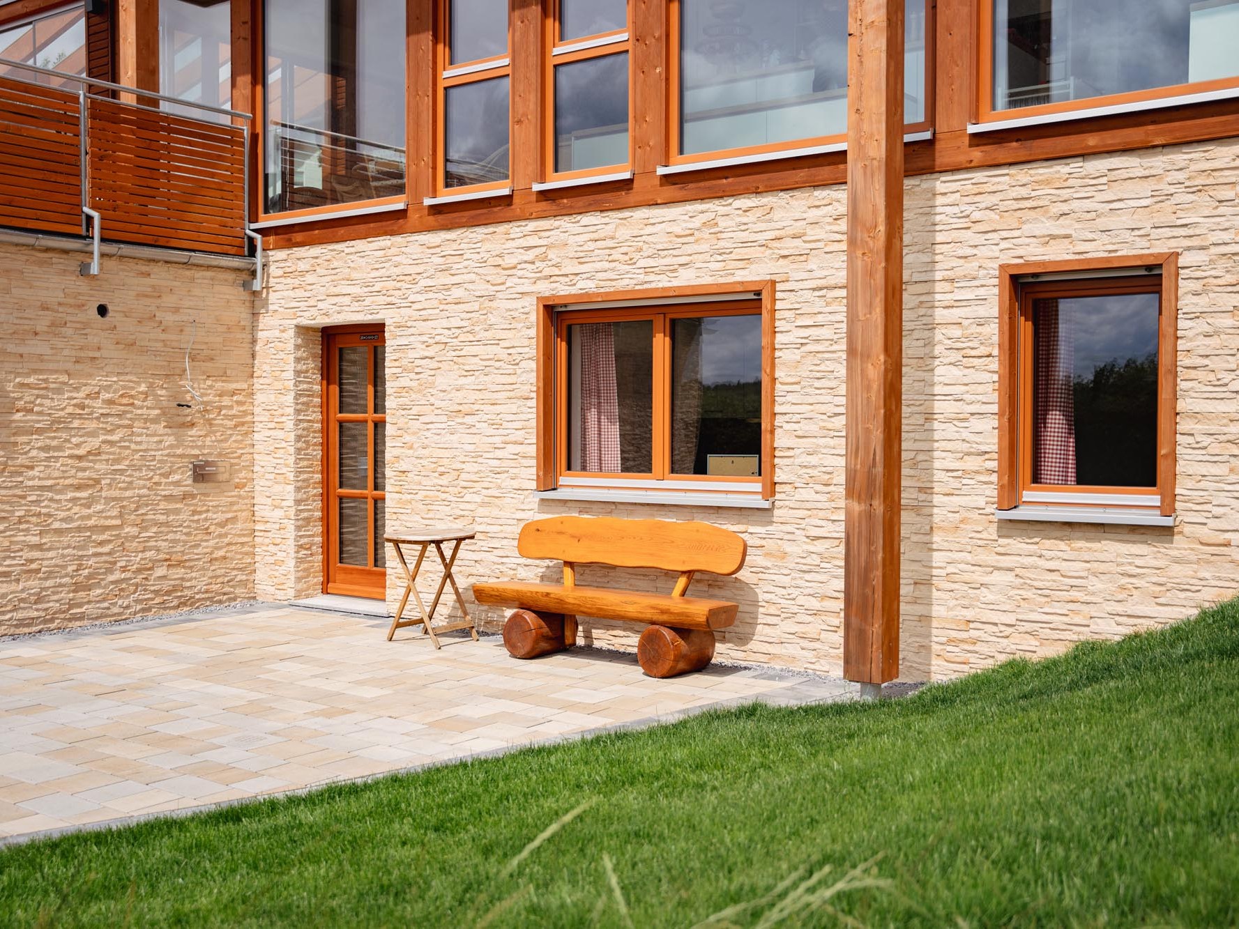 Gartenseitige Ansicht der Einliegerwohnung mit Holzfenstern und Natursteinfassade