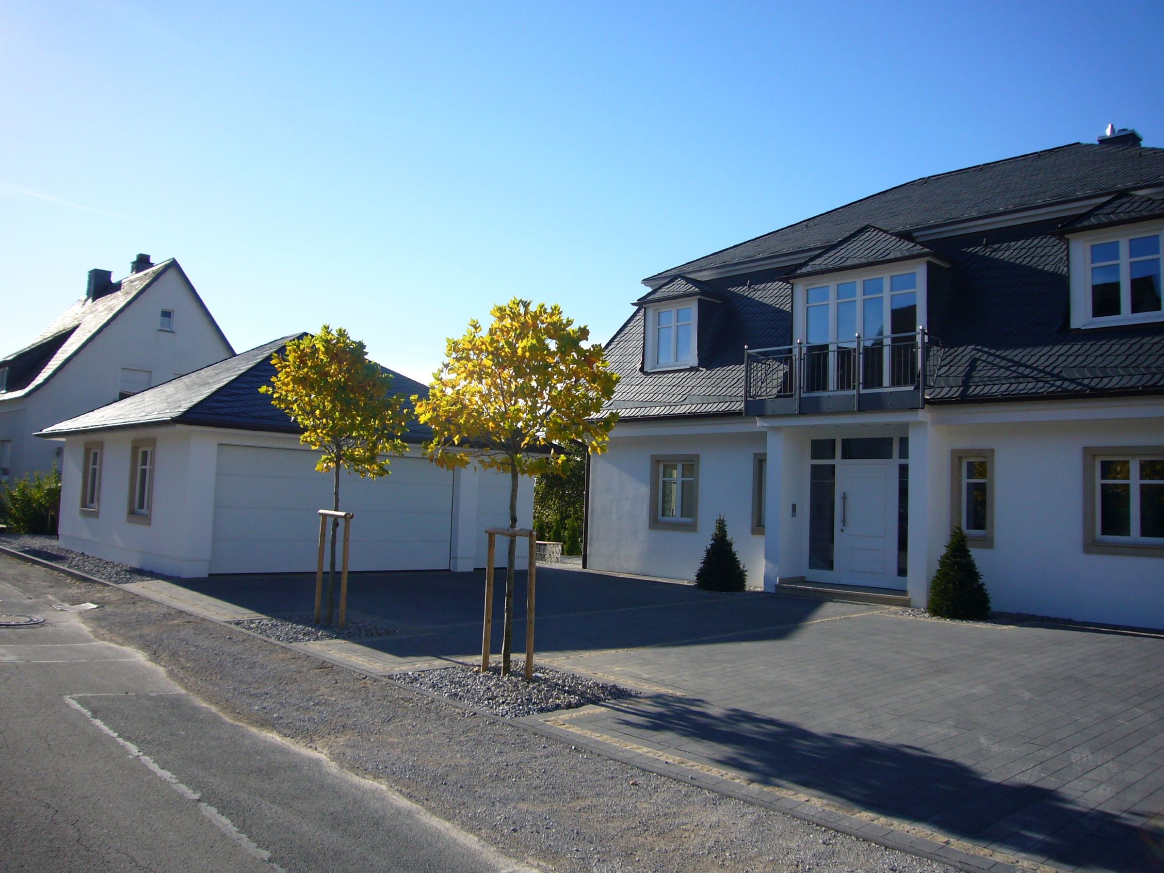 Einfamilienhaus mit Putzfassade und separater Doppelgarage in Straßenansicht