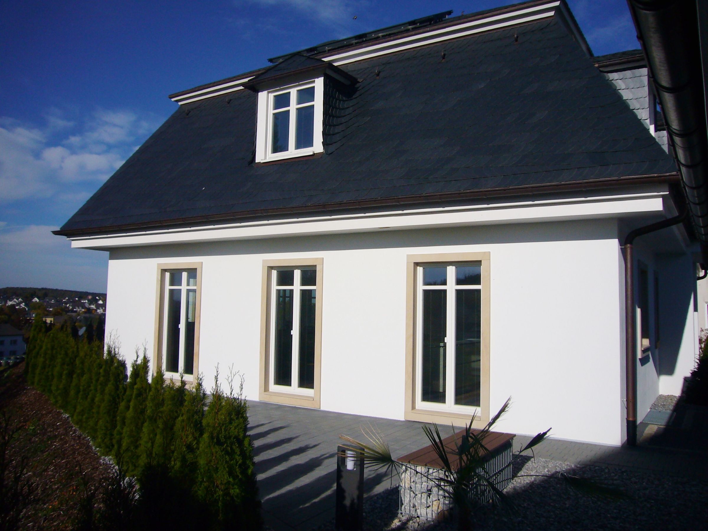 Gartenseite eines Wohnhauses mit Terrasse und bodentiefen Fenstern