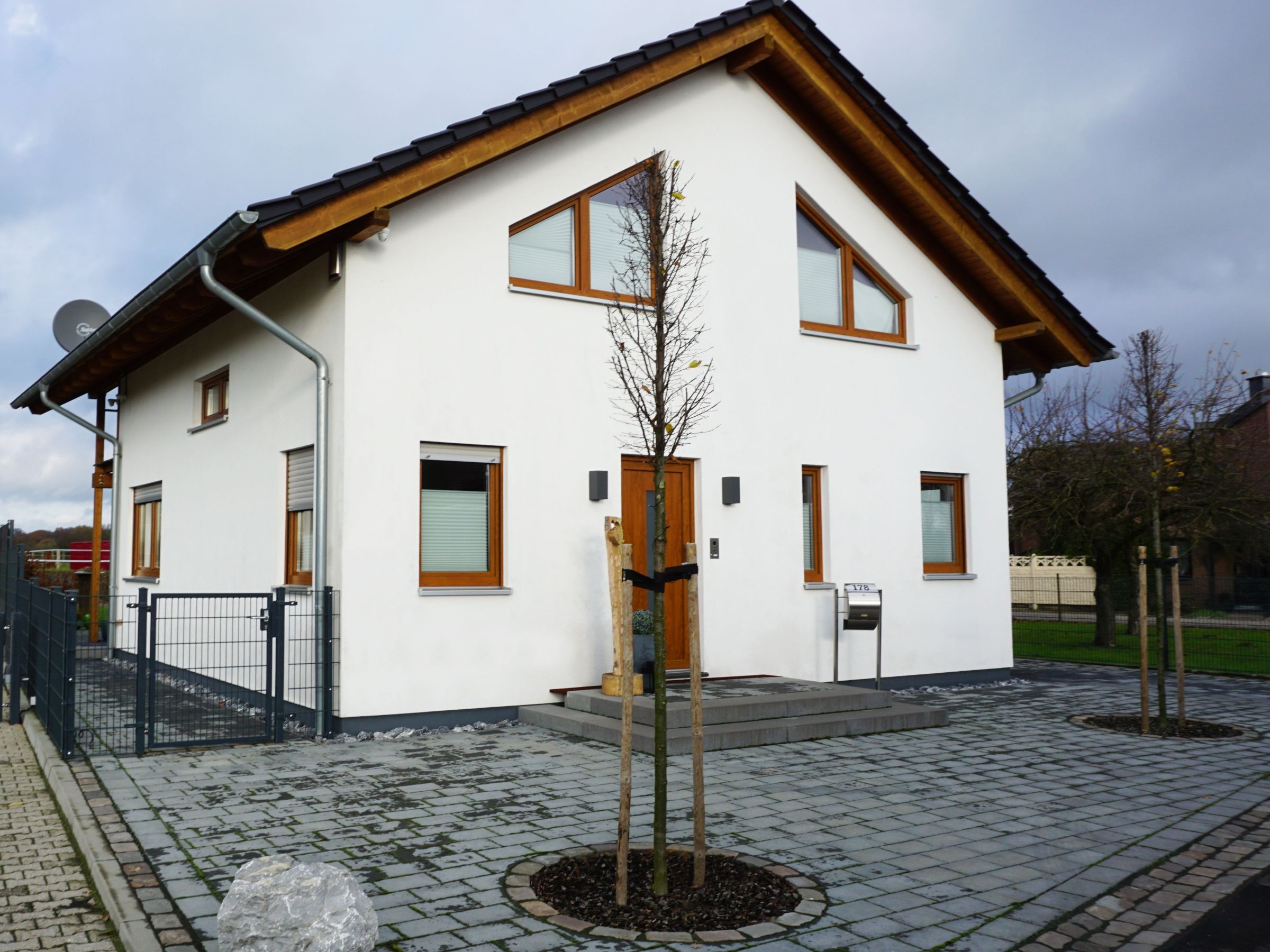 Eingangsbereich eines Einfamilienhauses mit Haustür, Fensteröffnungen und Putzfassade