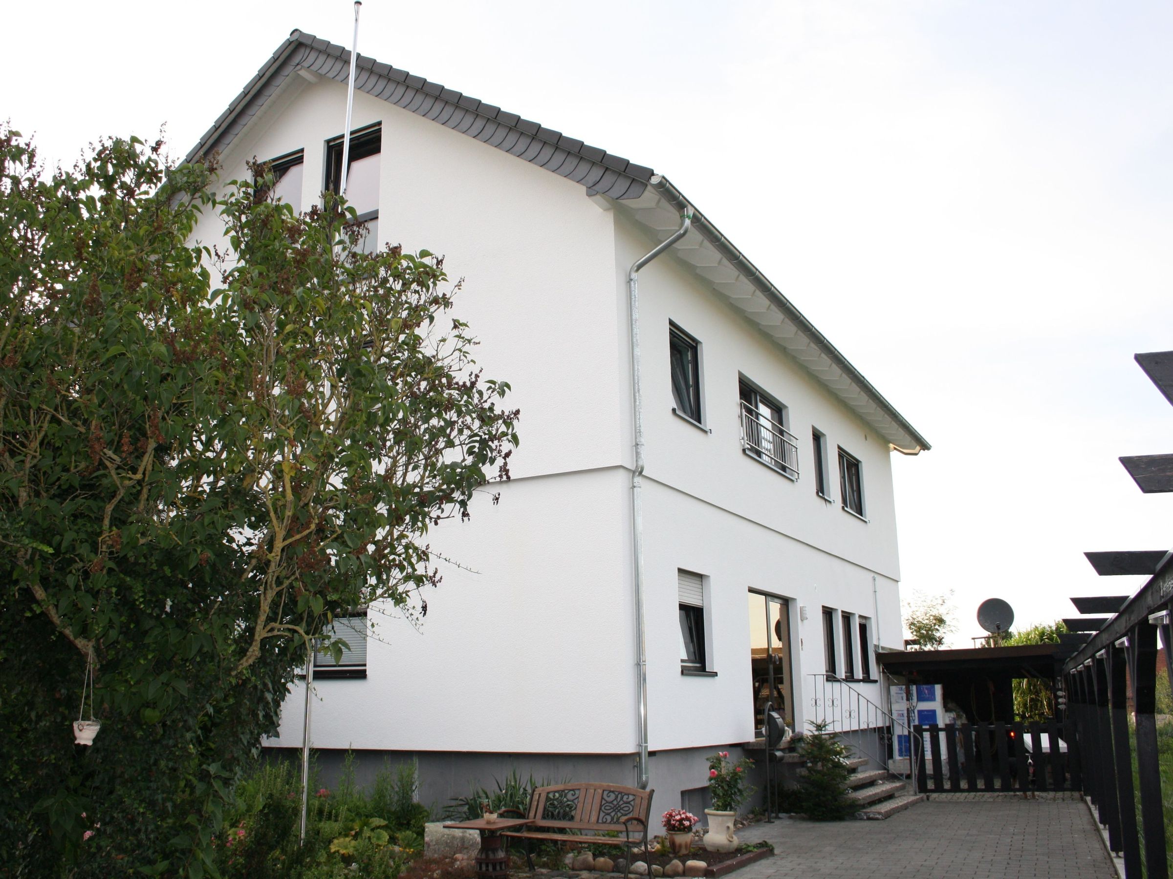 Seitenansicht des Zweifamilienhauses nach der Aufstockung mit Hauseingang