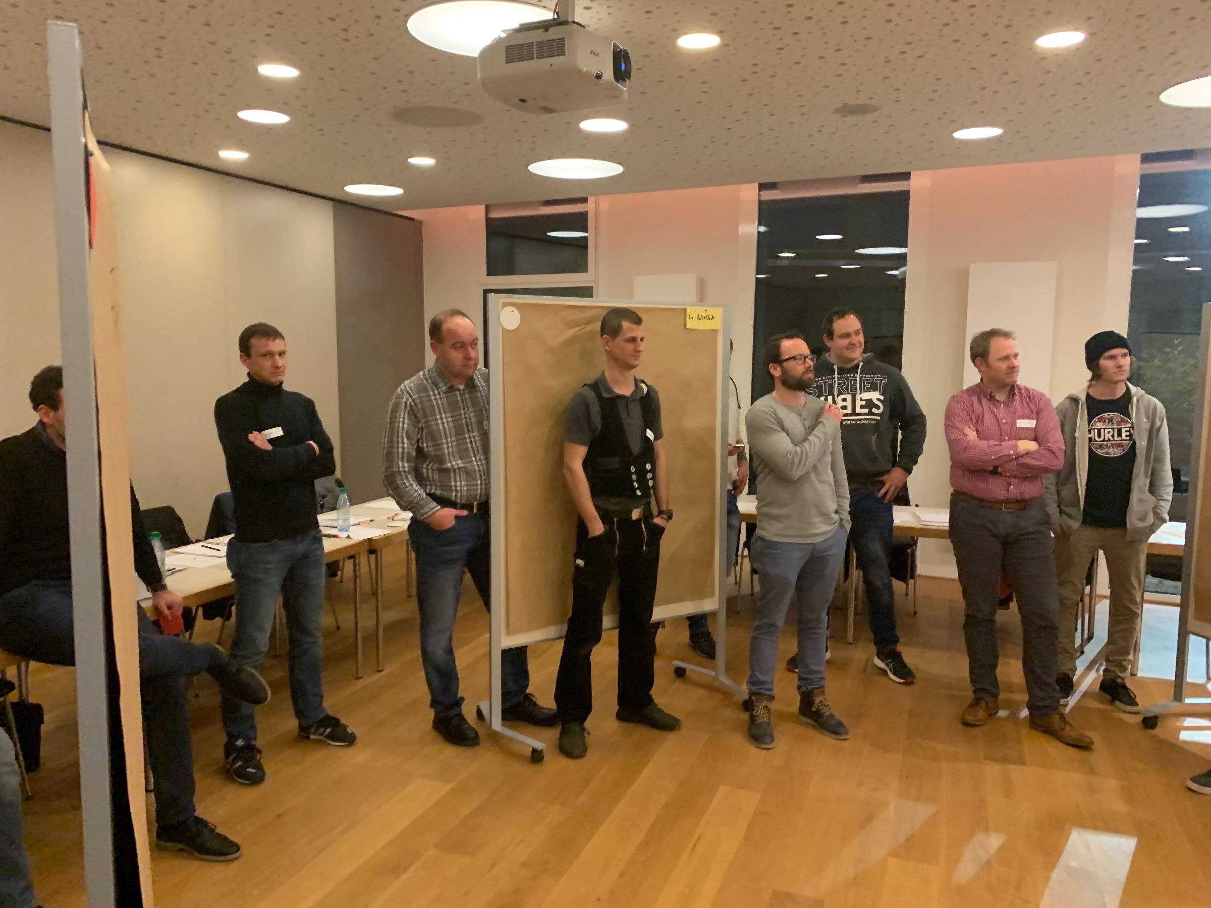Teilnehmende stehen im Seminarraum und diskutieren Inhalte eines Workshops zur Führungskompetenz