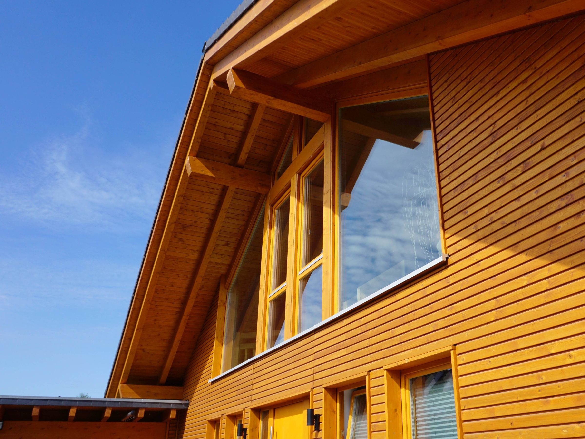 Detail der Holzfassade mit Fensteröffnungen und Dachüberstand