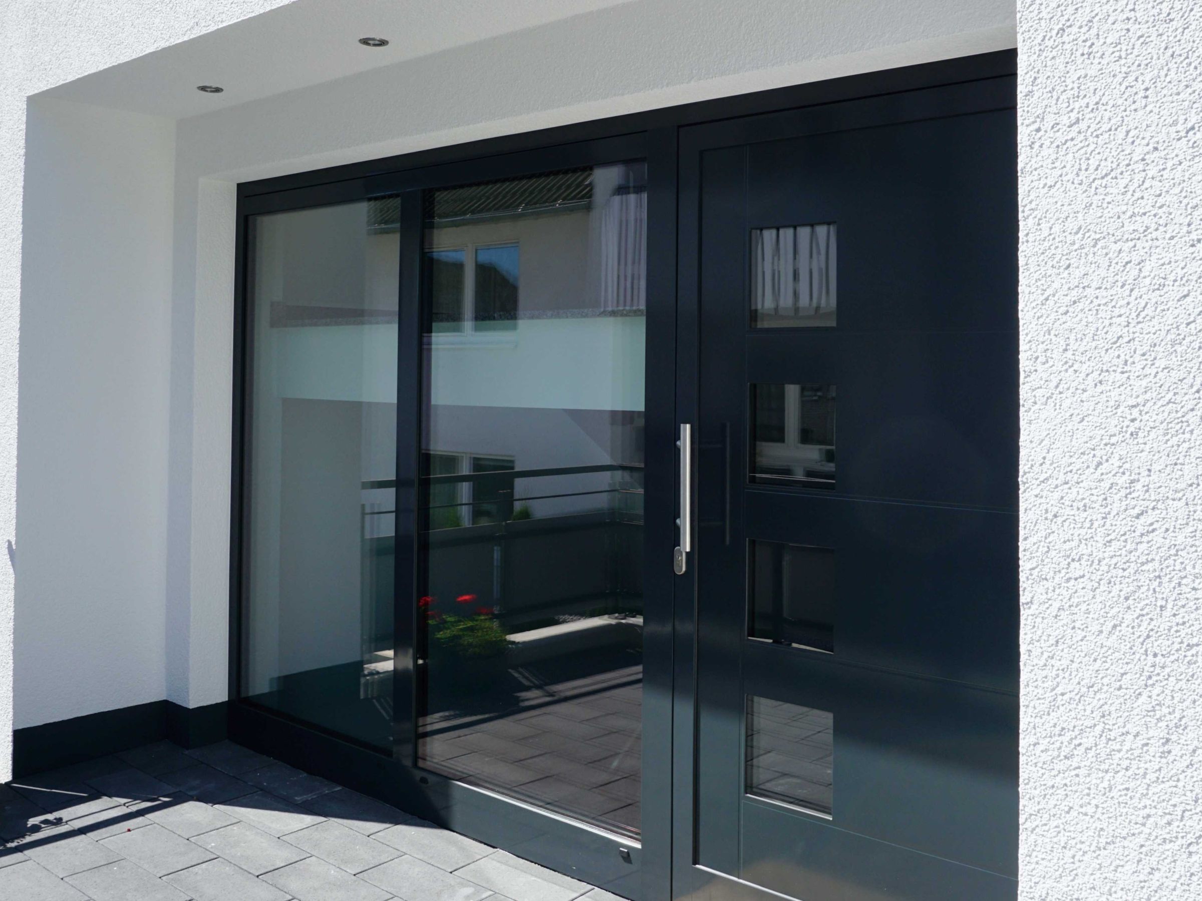 Hauseingang eines Mehrfamilienhauses mit dunkler Haustür und seitlicher Verglasung