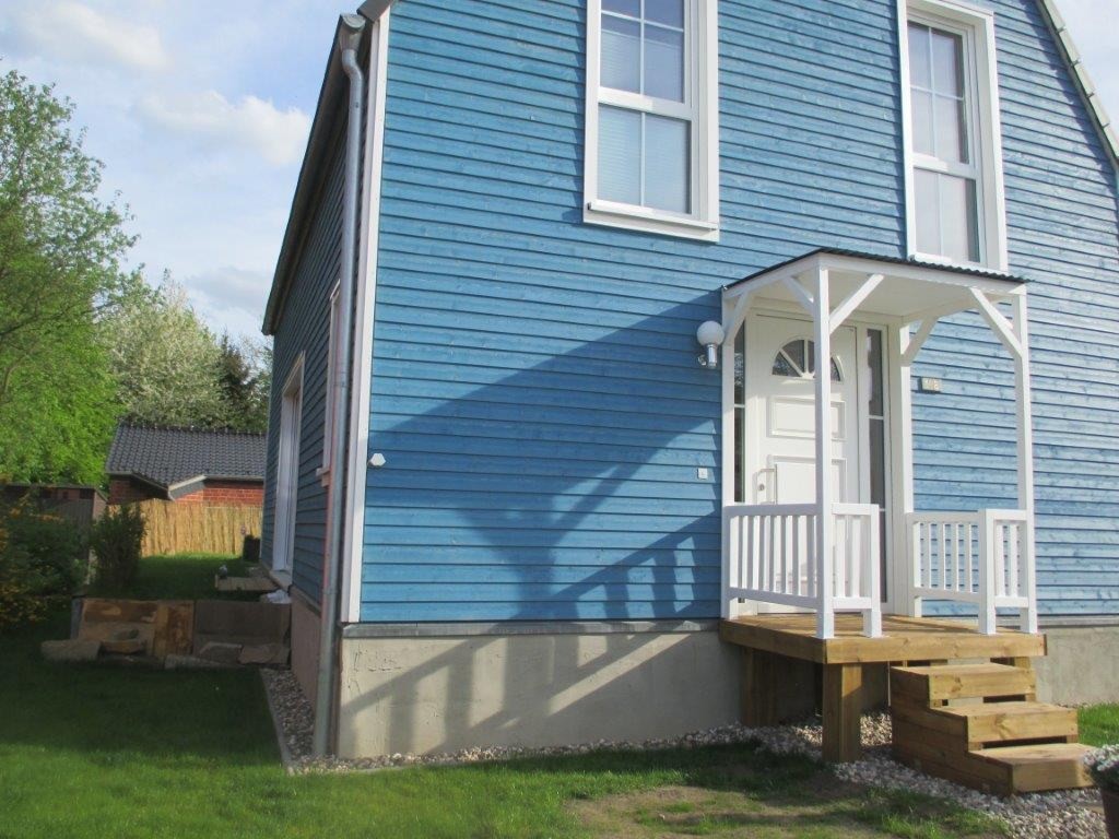 Hauseingang eines friesenblauen Holzhauses mit weißem Vordach