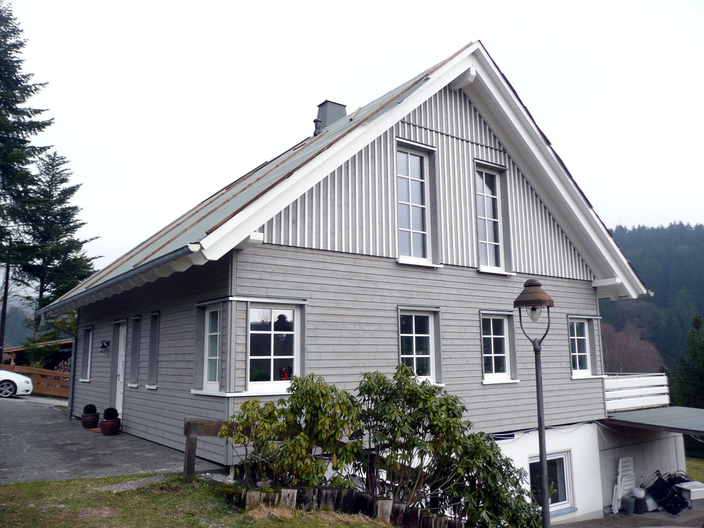 Giebelansicht eines Holzhauses mit Sprossenfenstern und Satteldach