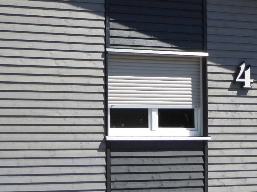 Detail der horizontalen Holzfassade mit differenzierten Farbtönen am Anbau aus Holz