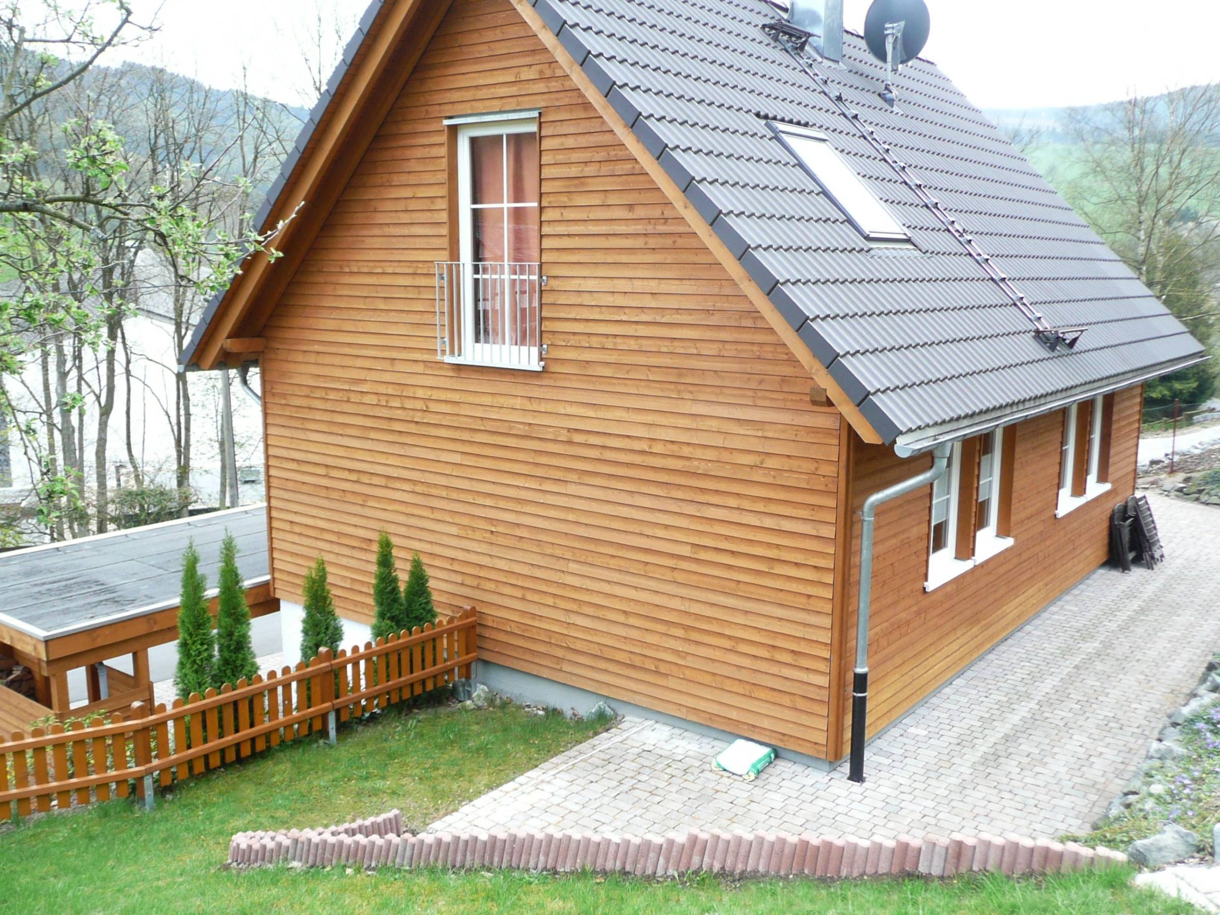 Rückansicht Haus Müller mit Satteldach, Holzfassade und gepflastertem Außenbereich