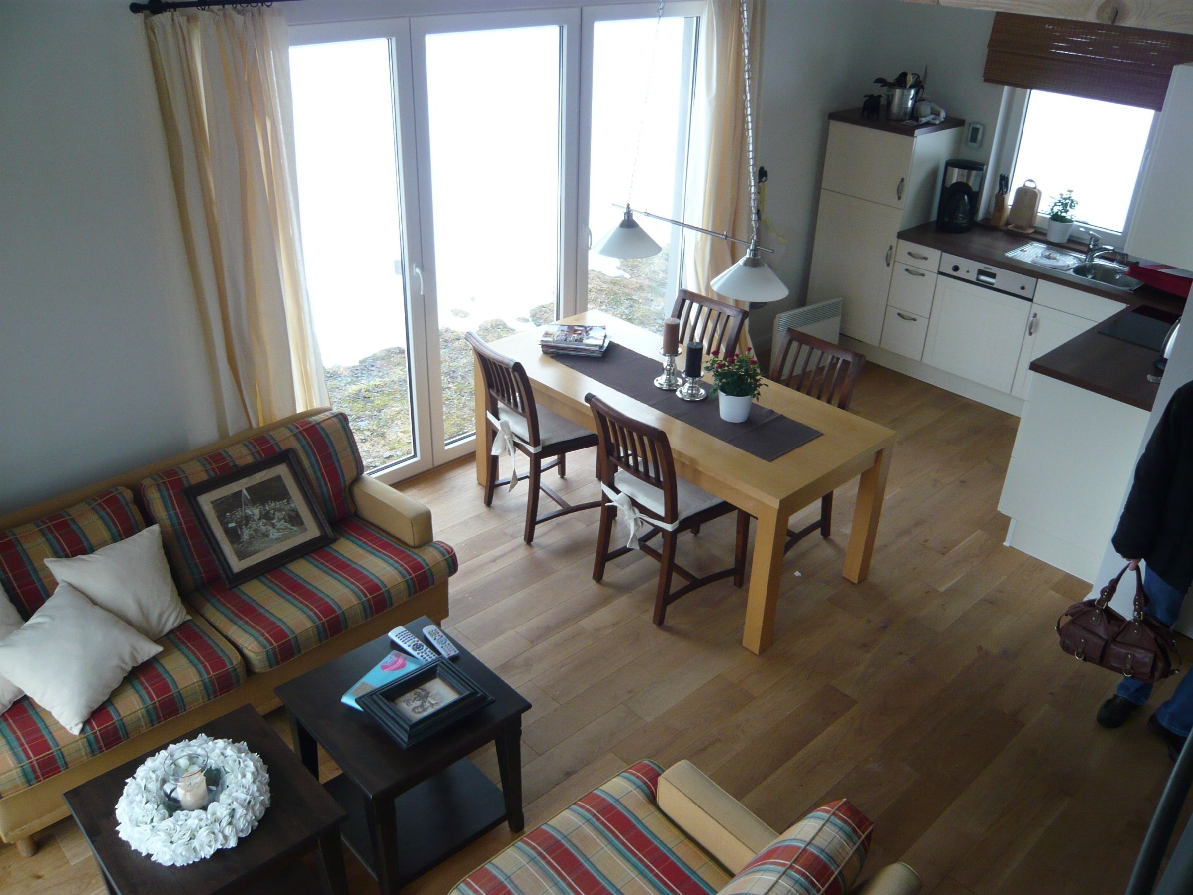 Offener Wohn- und Essbereich mit Holzboden, Küchenzeile und großer Fensterfront