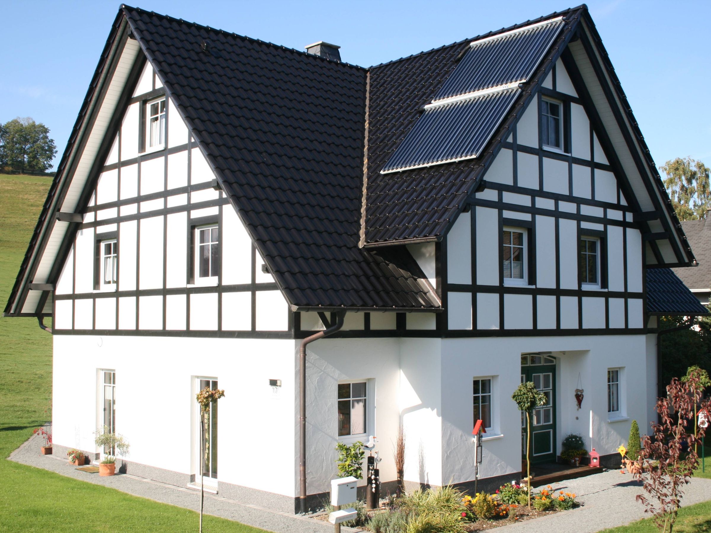 Giebelseite eines Fachwerkhauses mit schwarzer Holzkonstruktion und Putzfassade