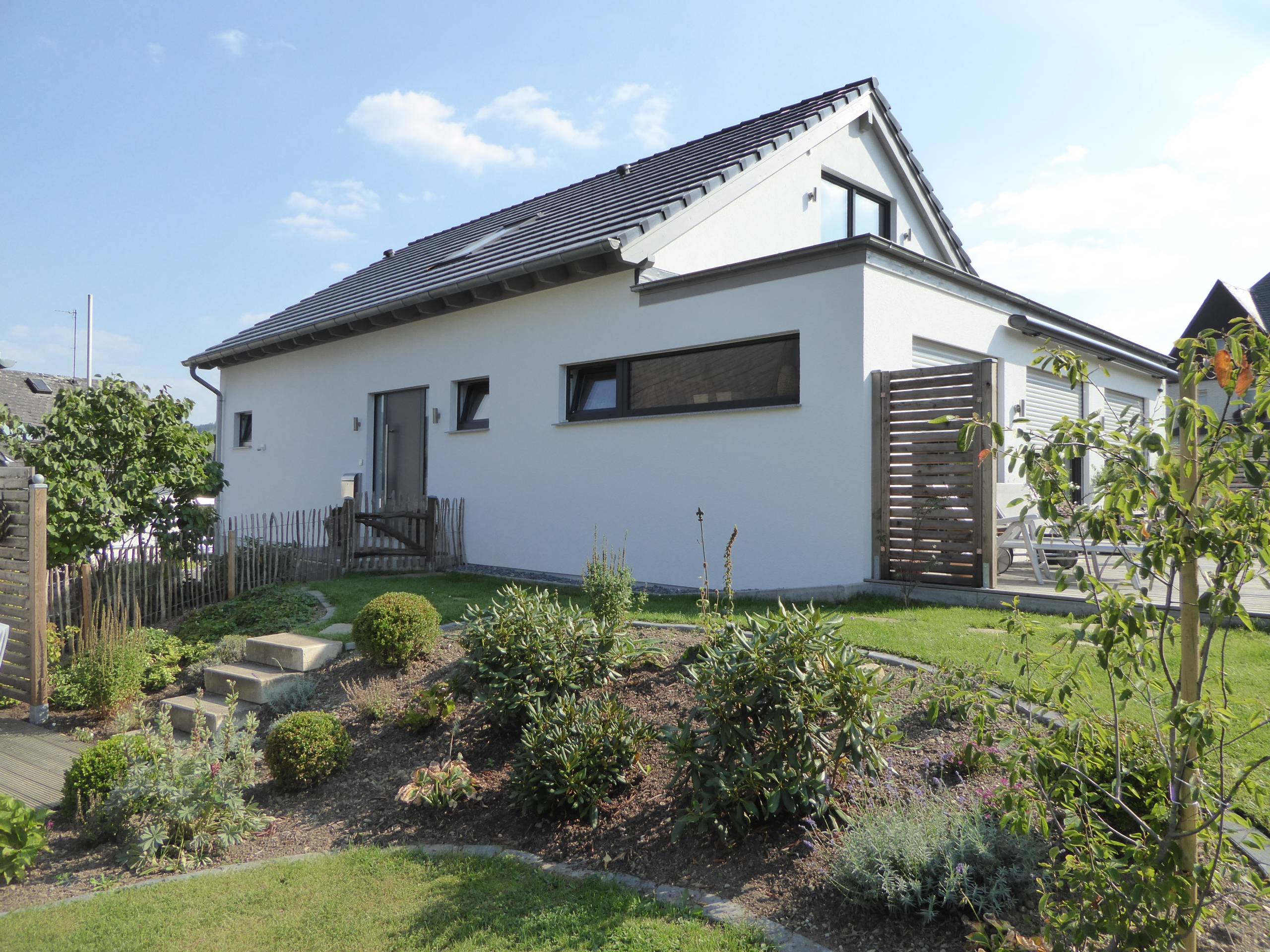 Seitliche Ansicht des Wohnhauses mit Terrasse, Holzsichtschutz und Gartenanlage