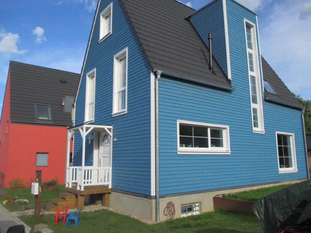 Detail der friesenblauen Holzfassade mit weiß gerahmten Fenstern