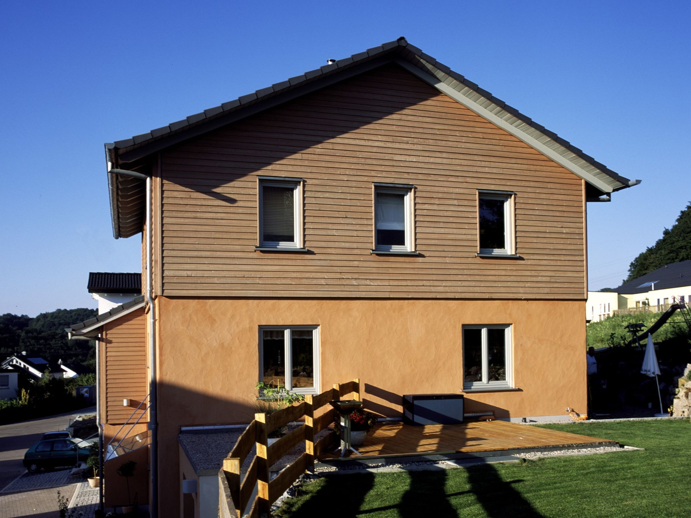 Rückansicht eines Mehrfamilienhauses mit Terrasse und Holzfassade