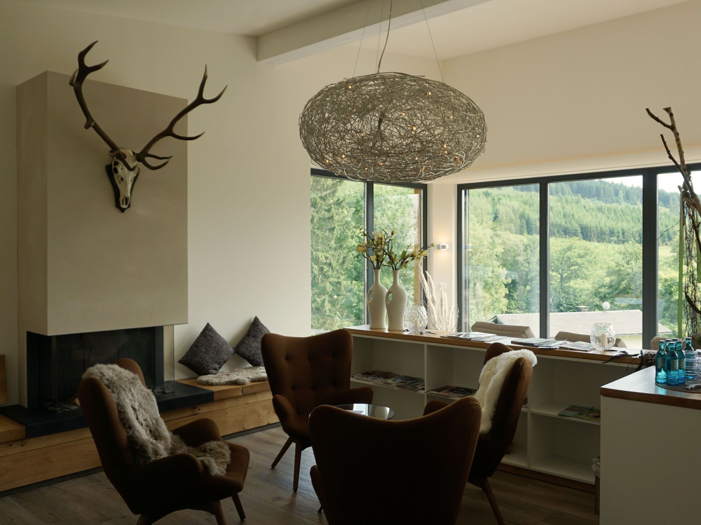 Ruheraum mit Kamin, Sitzbereich und großen Fensterflächen zur Natur