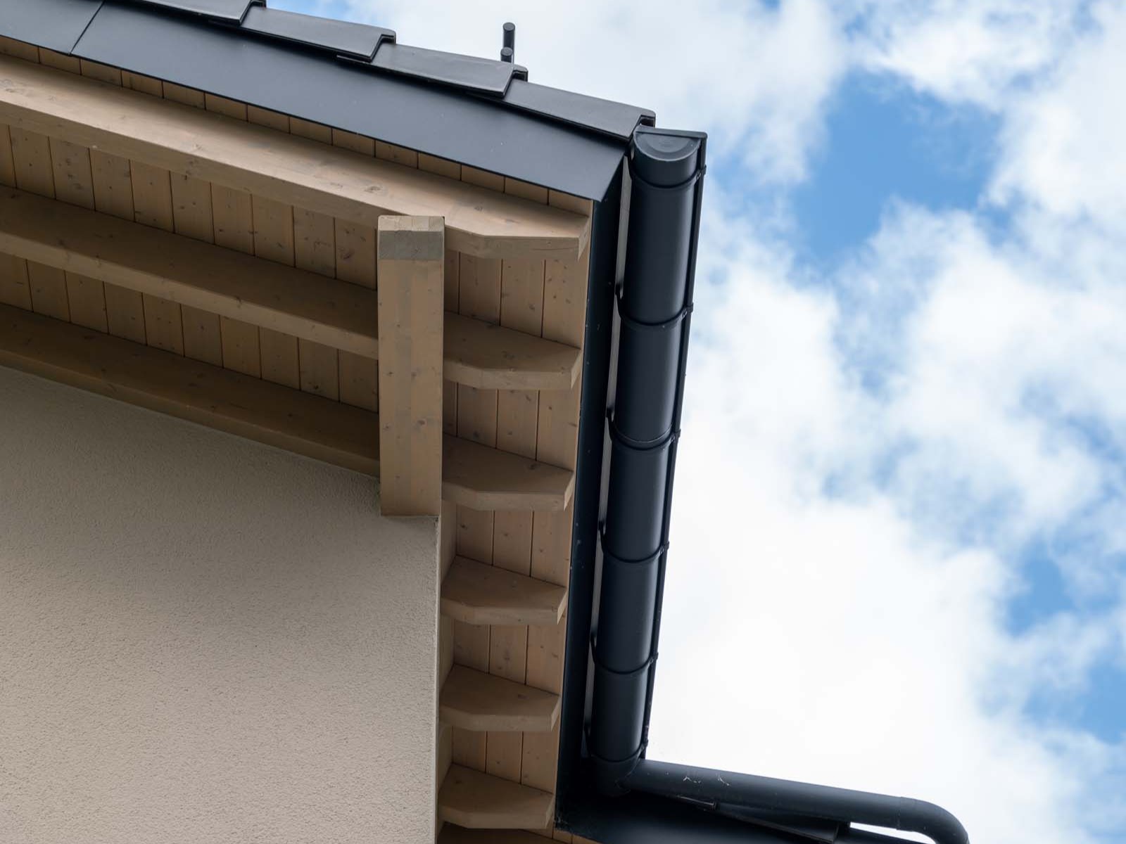 Traufdetail eines Mehrfamilienhauses mit sichtbarer Holzkonstruktion und Dachrinne