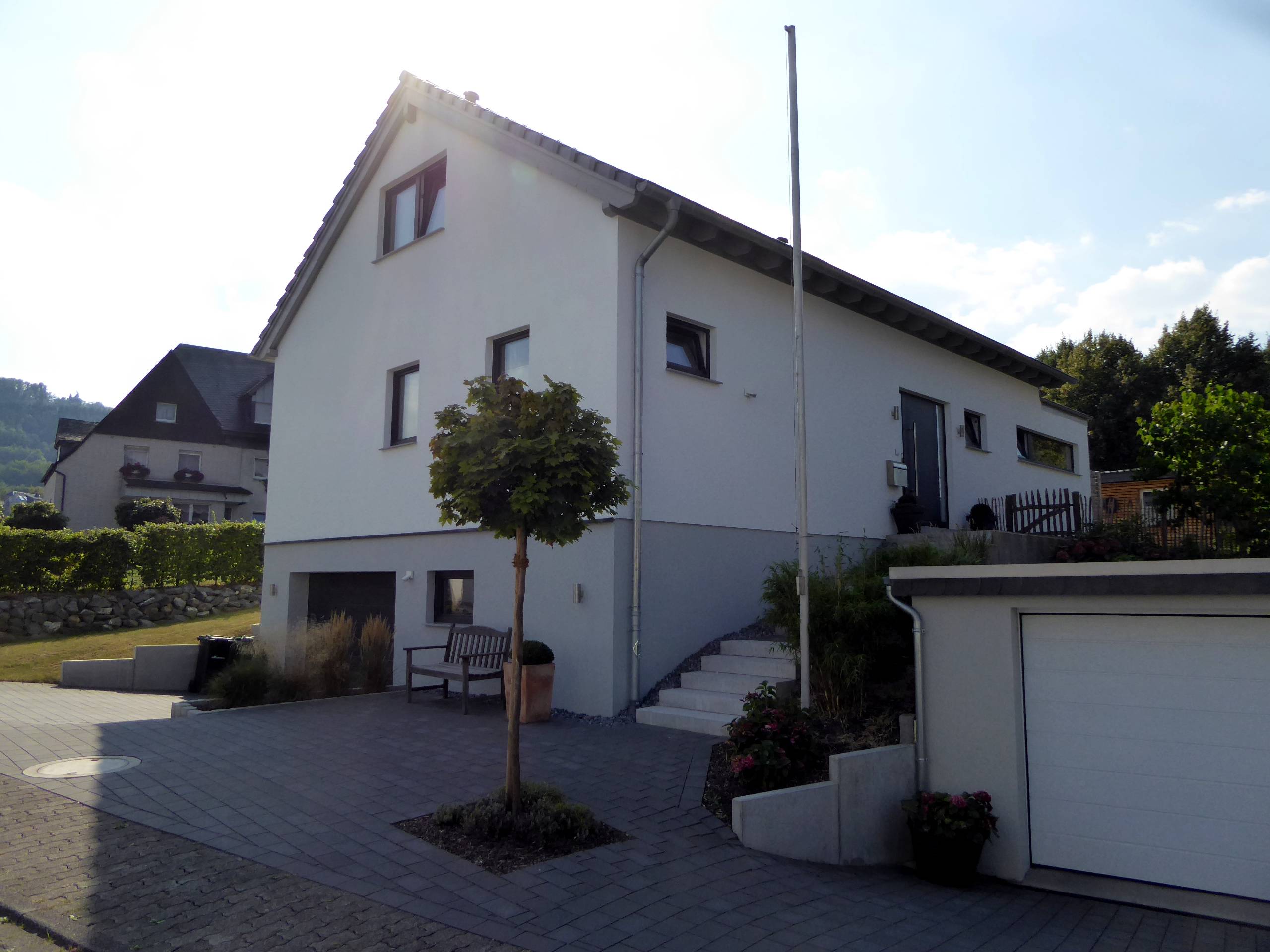 Eingangsansicht des Wohnhauses mit Treppe, Garage und klarer Fassadengliederung