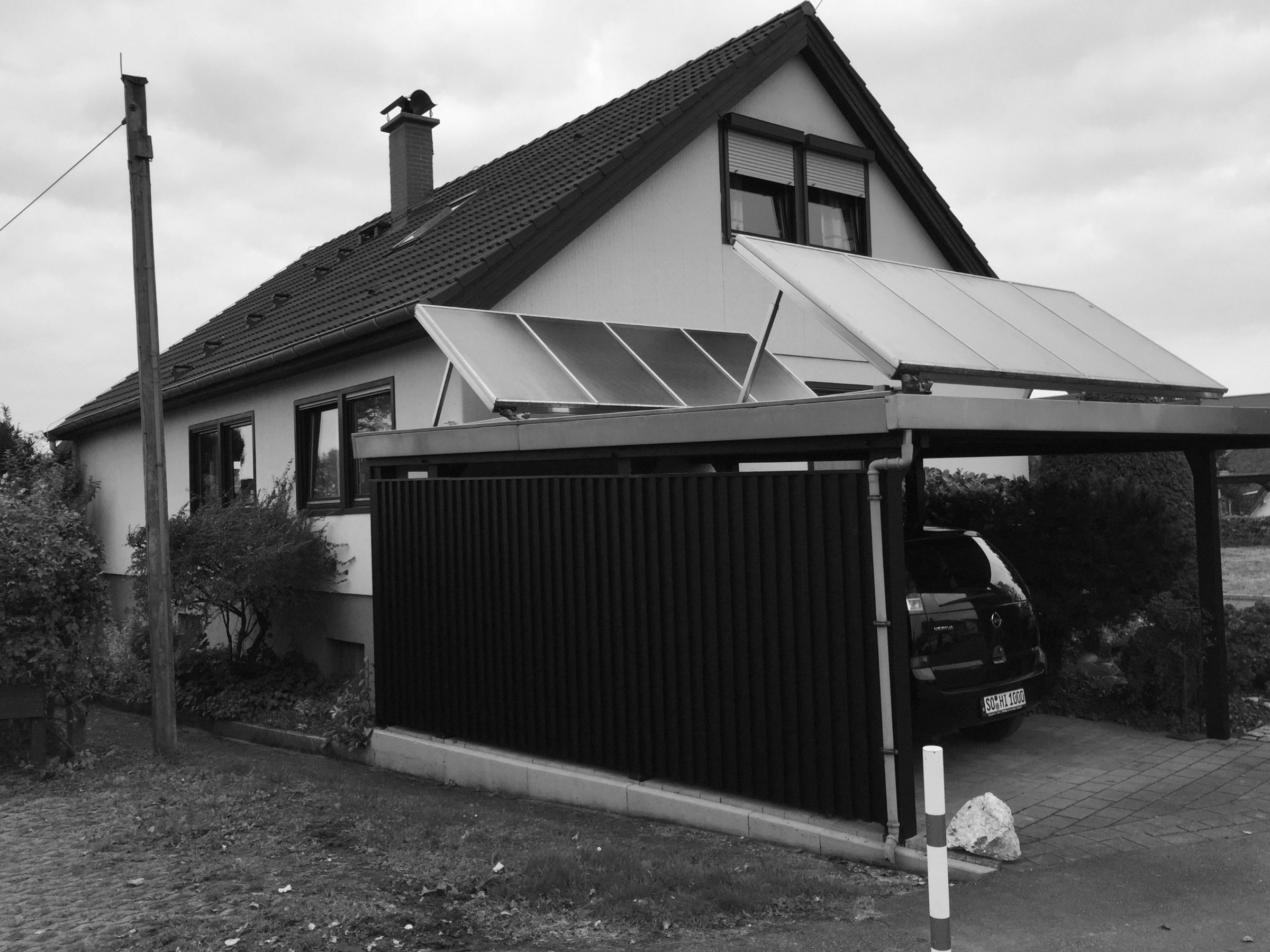 Bestandsgebäude vor der Aufstockung mit Carport und angrenzendem Wohnhaus
