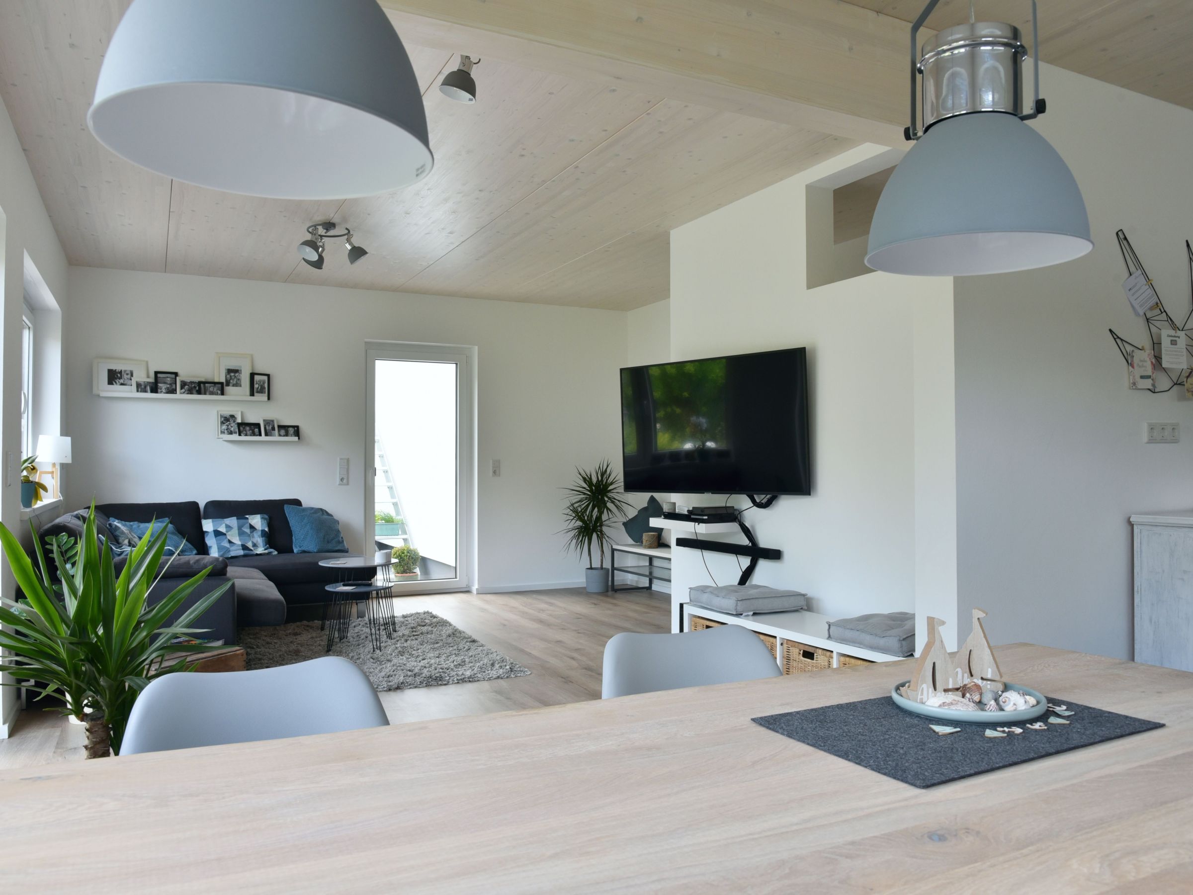 Großzügiger Wohn- und Essbereich mit offener Küche, Holzdecke und bodentiefen Fenstern