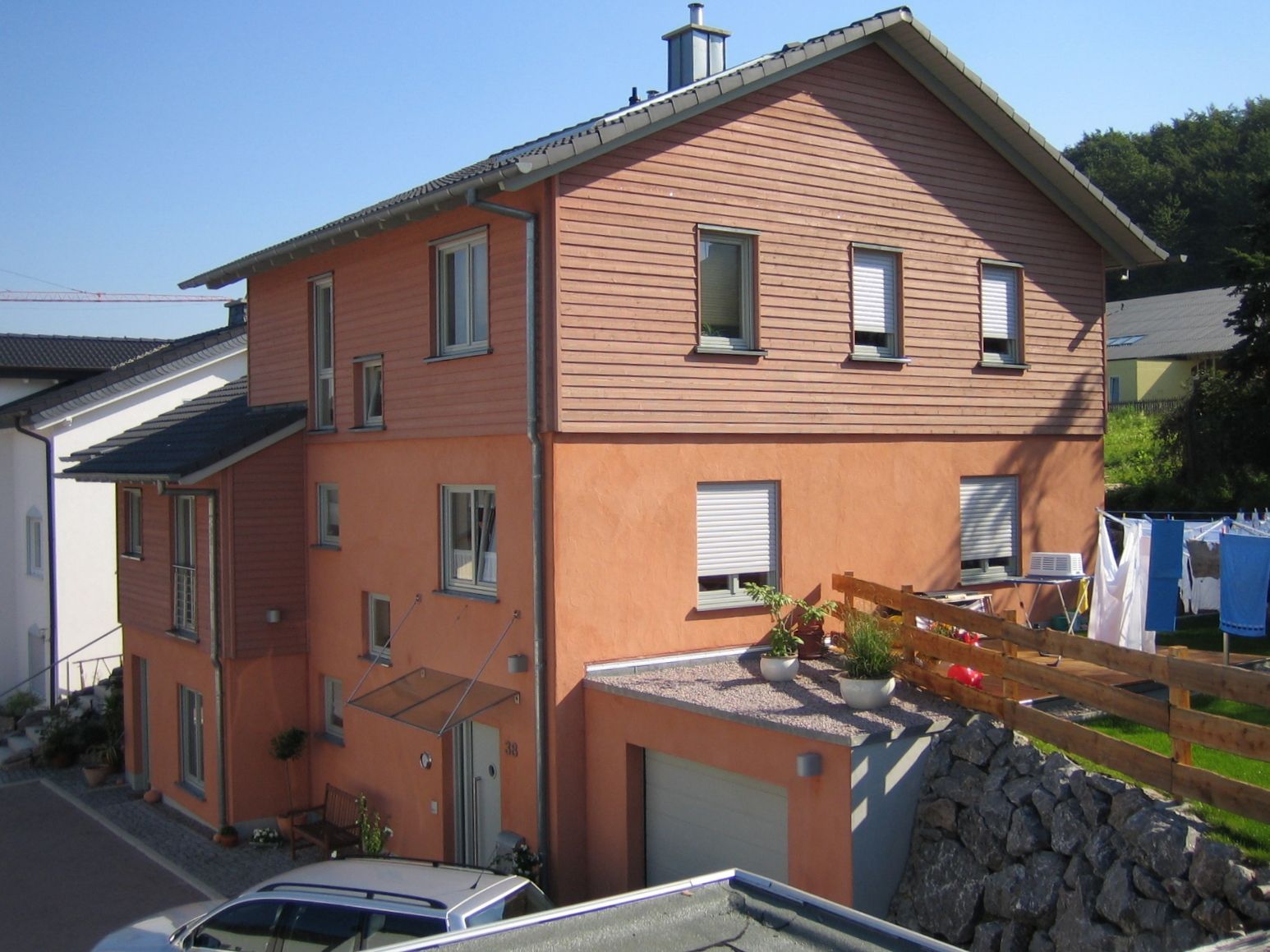 Straßenansicht eines Mehrfamilienhauses mit terracottafarbener Fassade und Garage