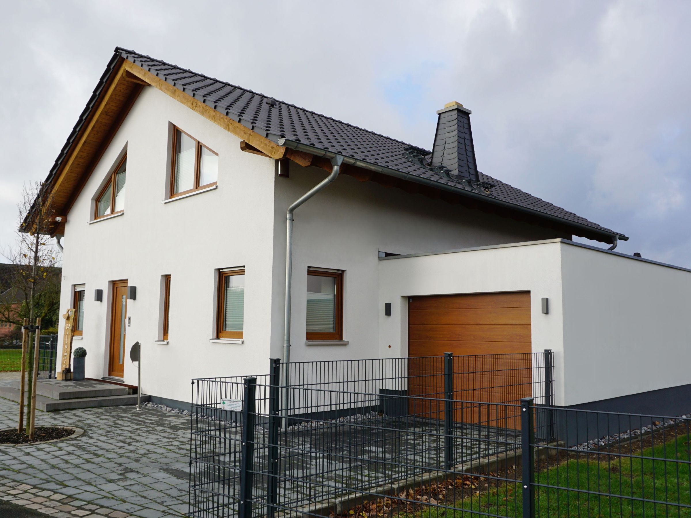 Einfamilienhaus mit weißer Putzfassade, Satteldach und angebauter Garage
