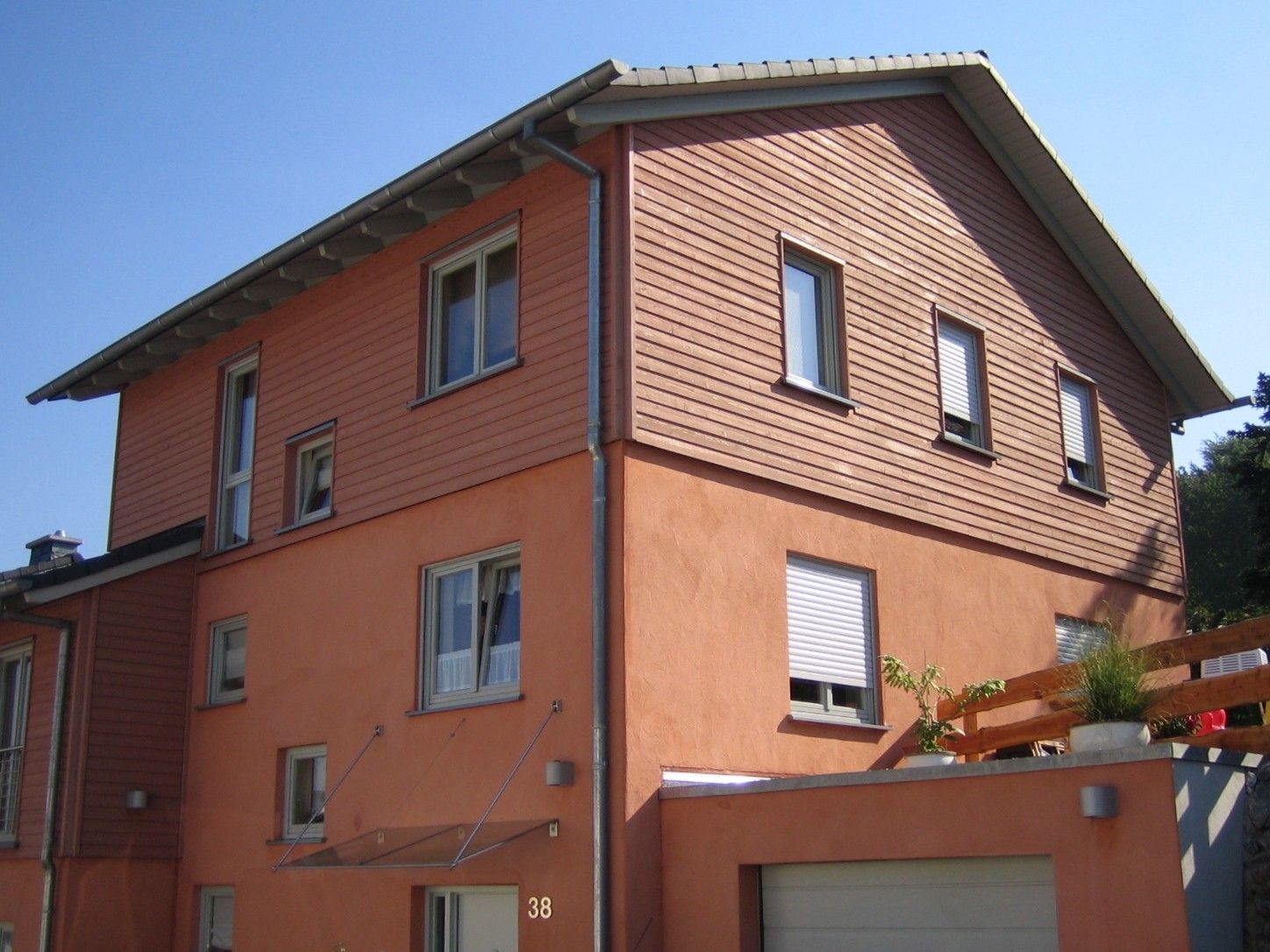 Seitenansicht eines Wohnhauses mit horizontaler Holzschalung im Farbton Terracotta