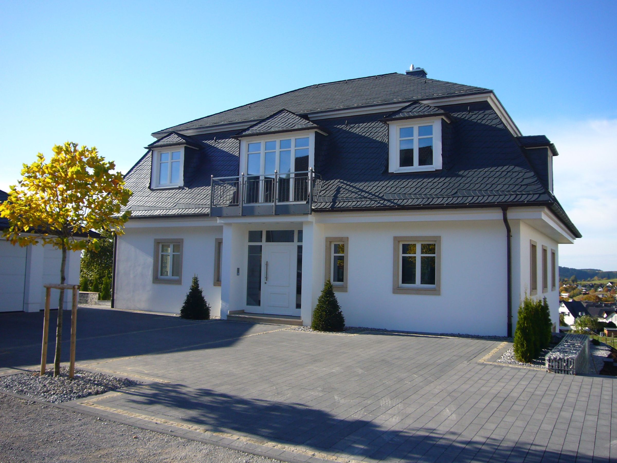 Frontalansicht eines Einfamilienhauses mit Mansarddach und Putzfassade