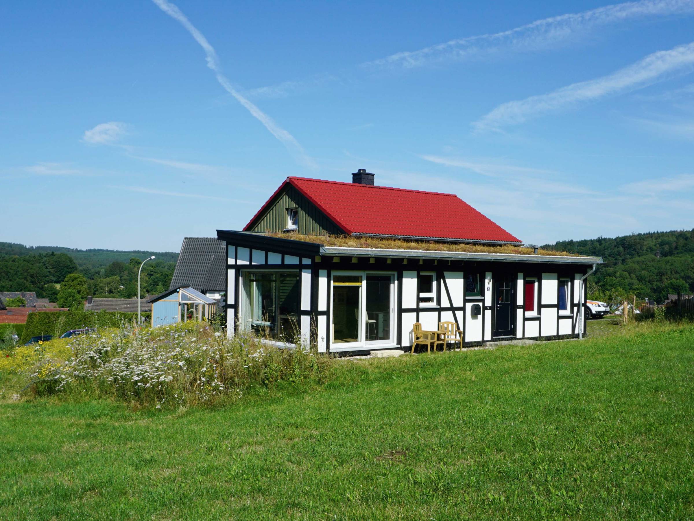 Gesamtansicht des Holzhauses mit Fachwerkfassade, Gründach und freier Lage im Grünen